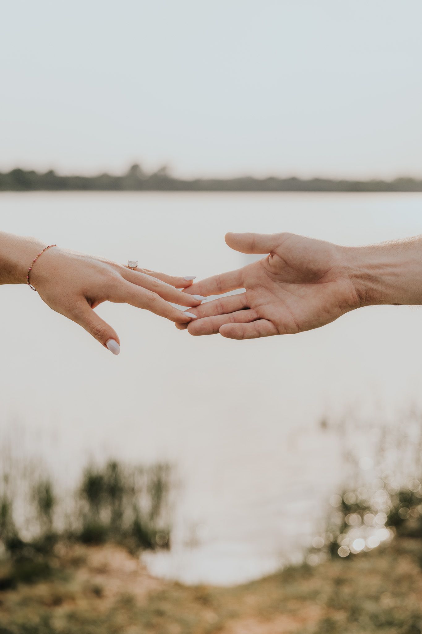 Two hands reaching towards each other against a soft white background in a tender gesture of connection.