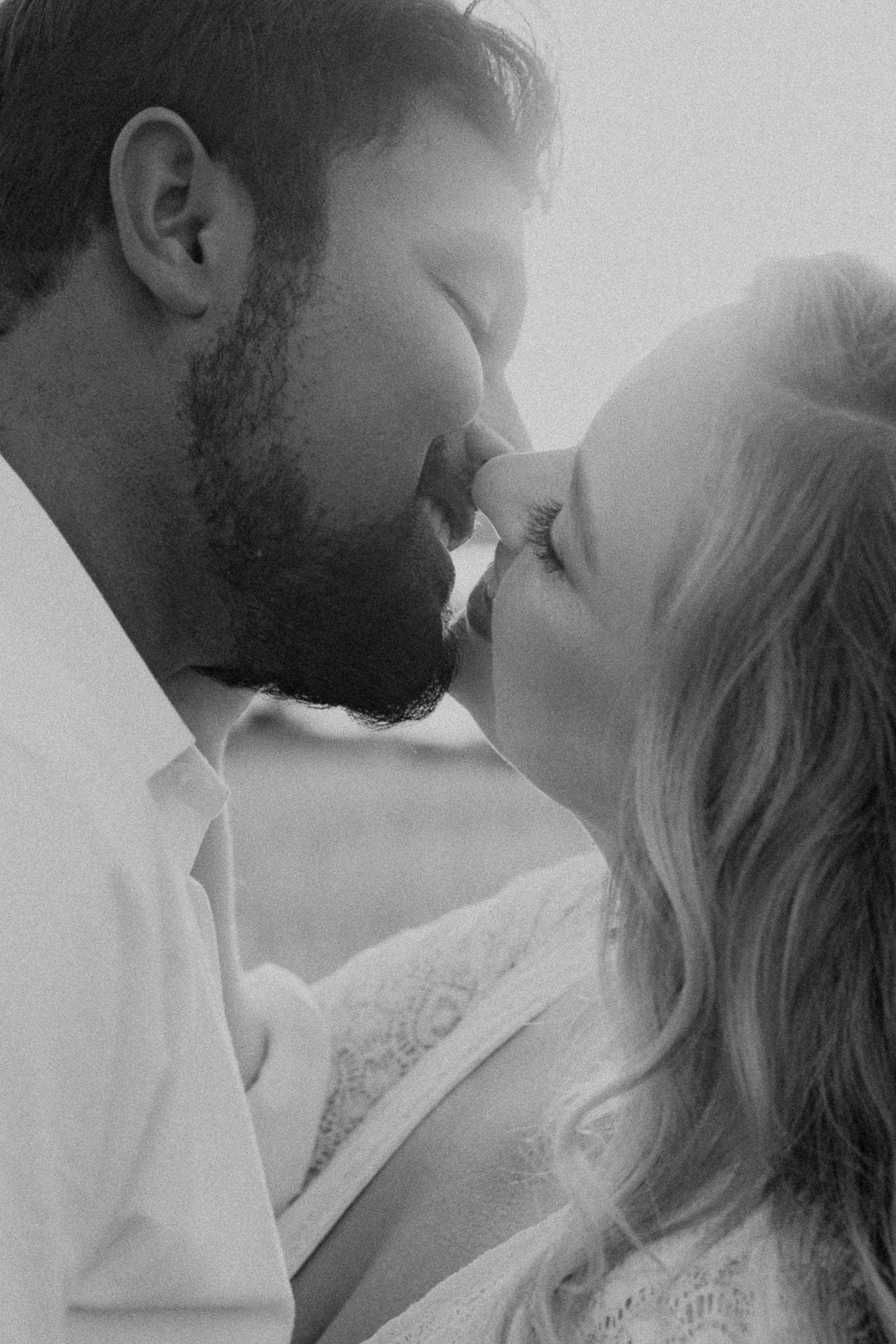 Intimate black and white portrait of couple sharing romantic kiss.