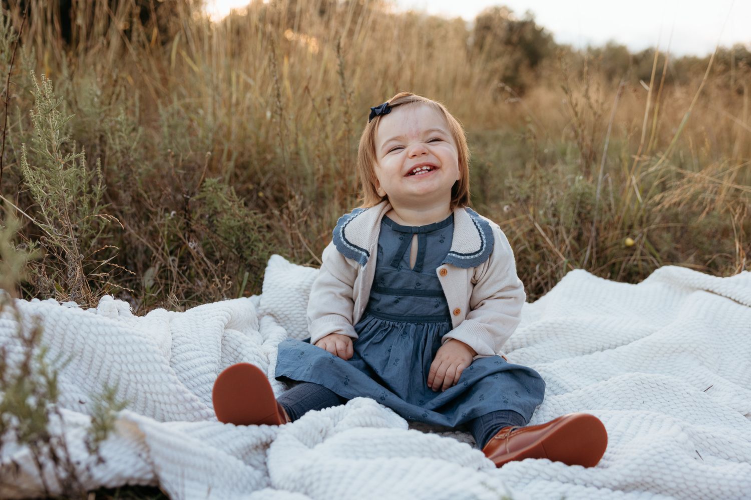 Candid family photos on white blanket during outdoor sunset photo session.
