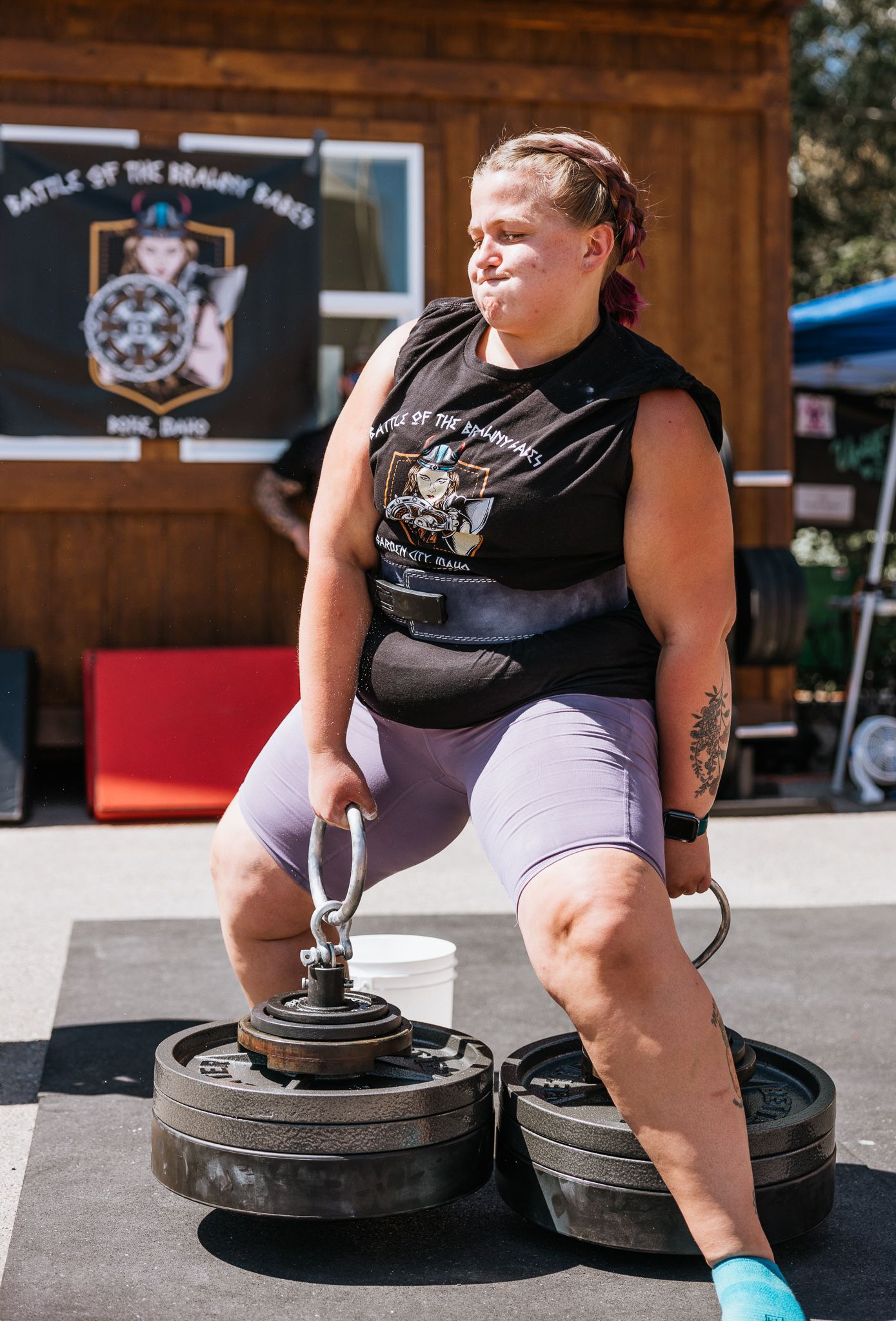 Athlete preparing for a strength competition by sitting on weighted equipment outdoors.