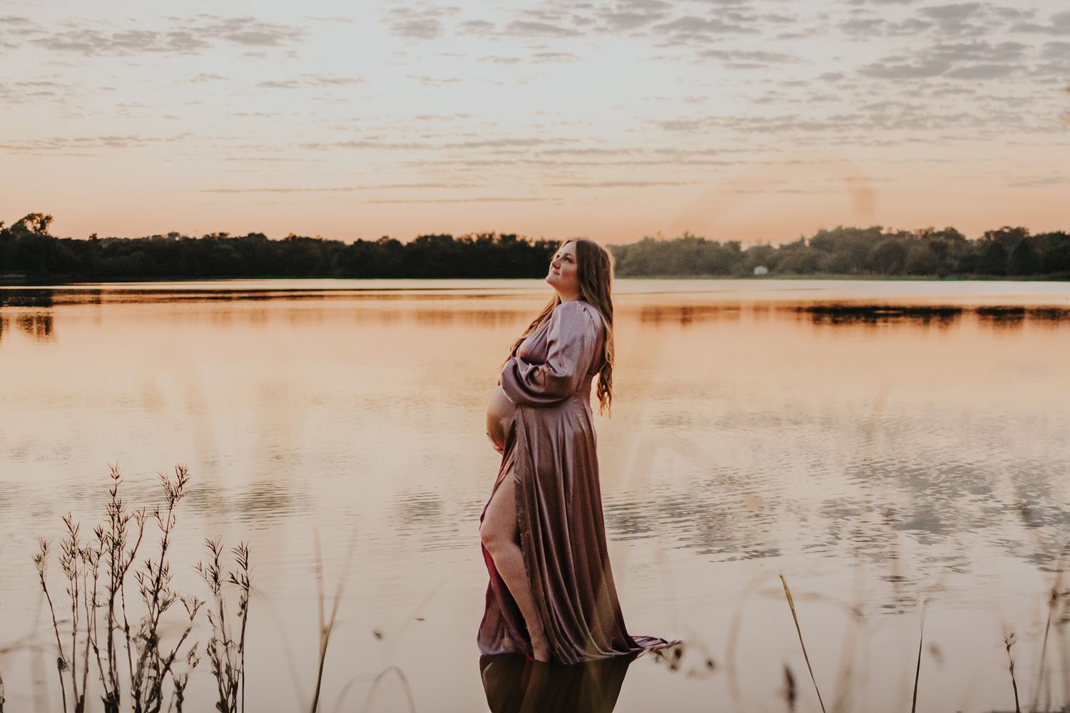Serene lakeside scene at sunset with figure standing by calm waters.