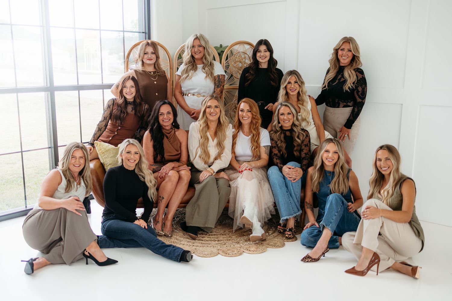 Group of twelve women posing together in a bright white studio, dressed in stylish boho outfits for a professional photo shoot.