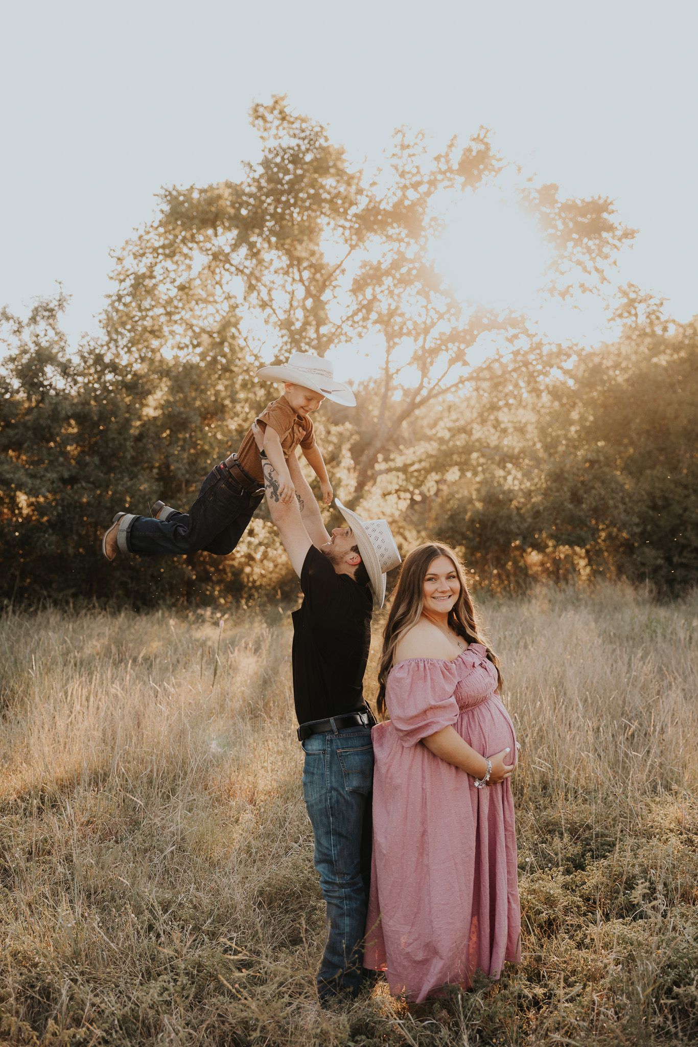 A couple embraces in a sun-drenched field during golden hour.
