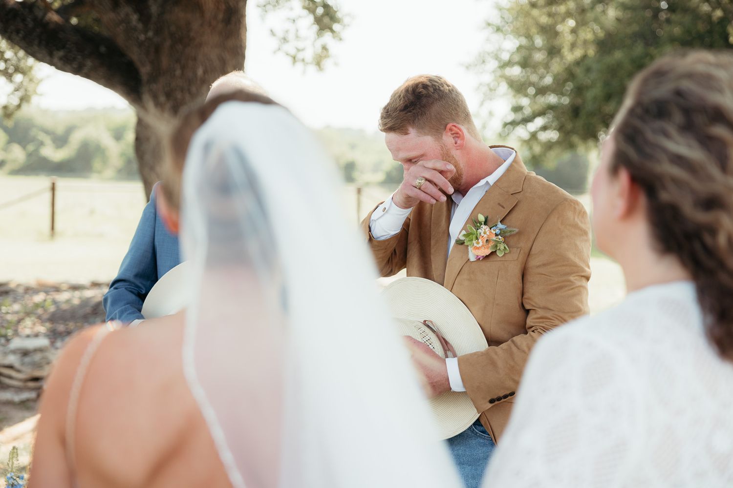 A wedding couple shares an intimate moment under a tree in soft natural light.