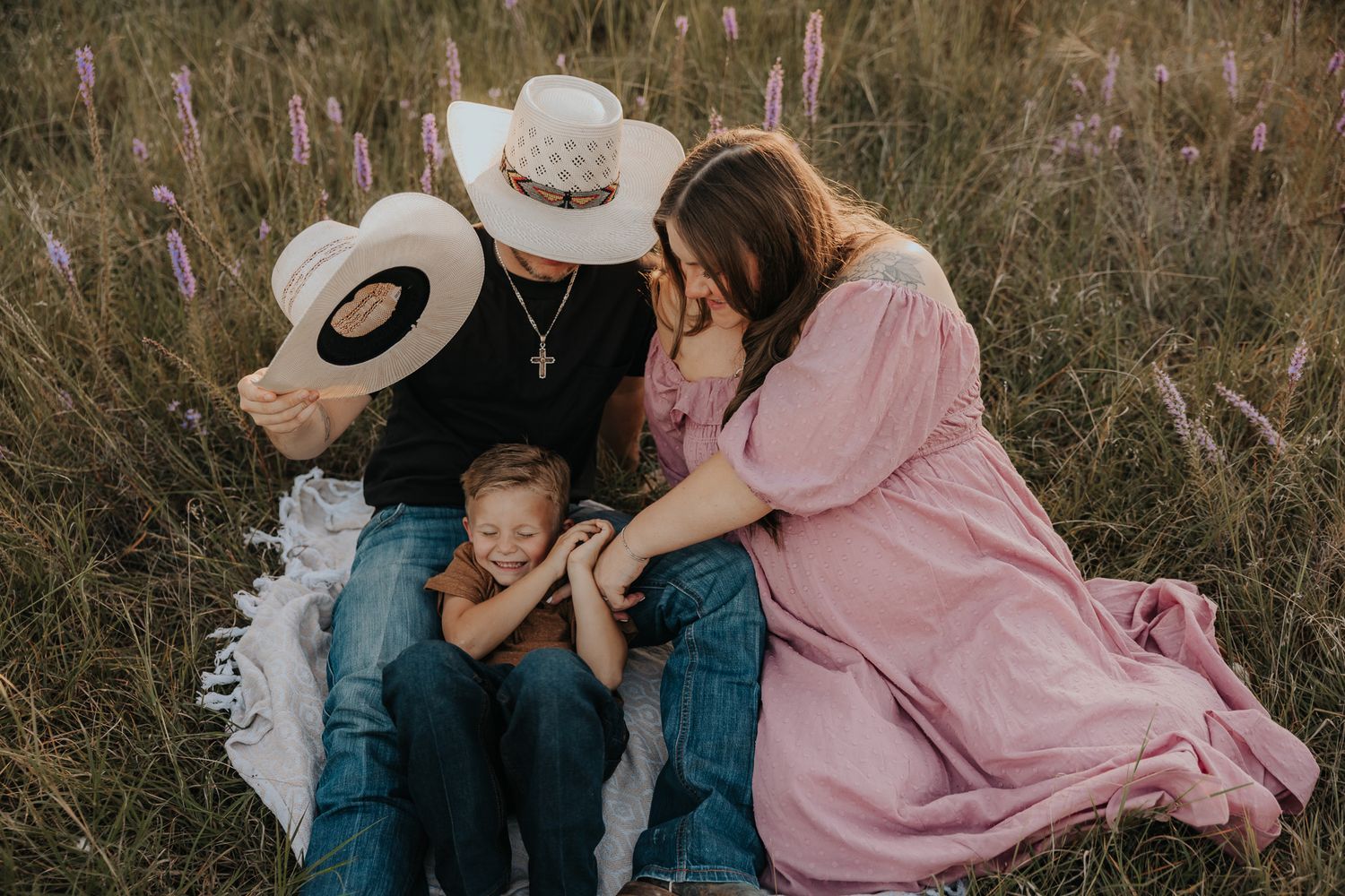 A family shares intimate moments together in a field during golden hour.