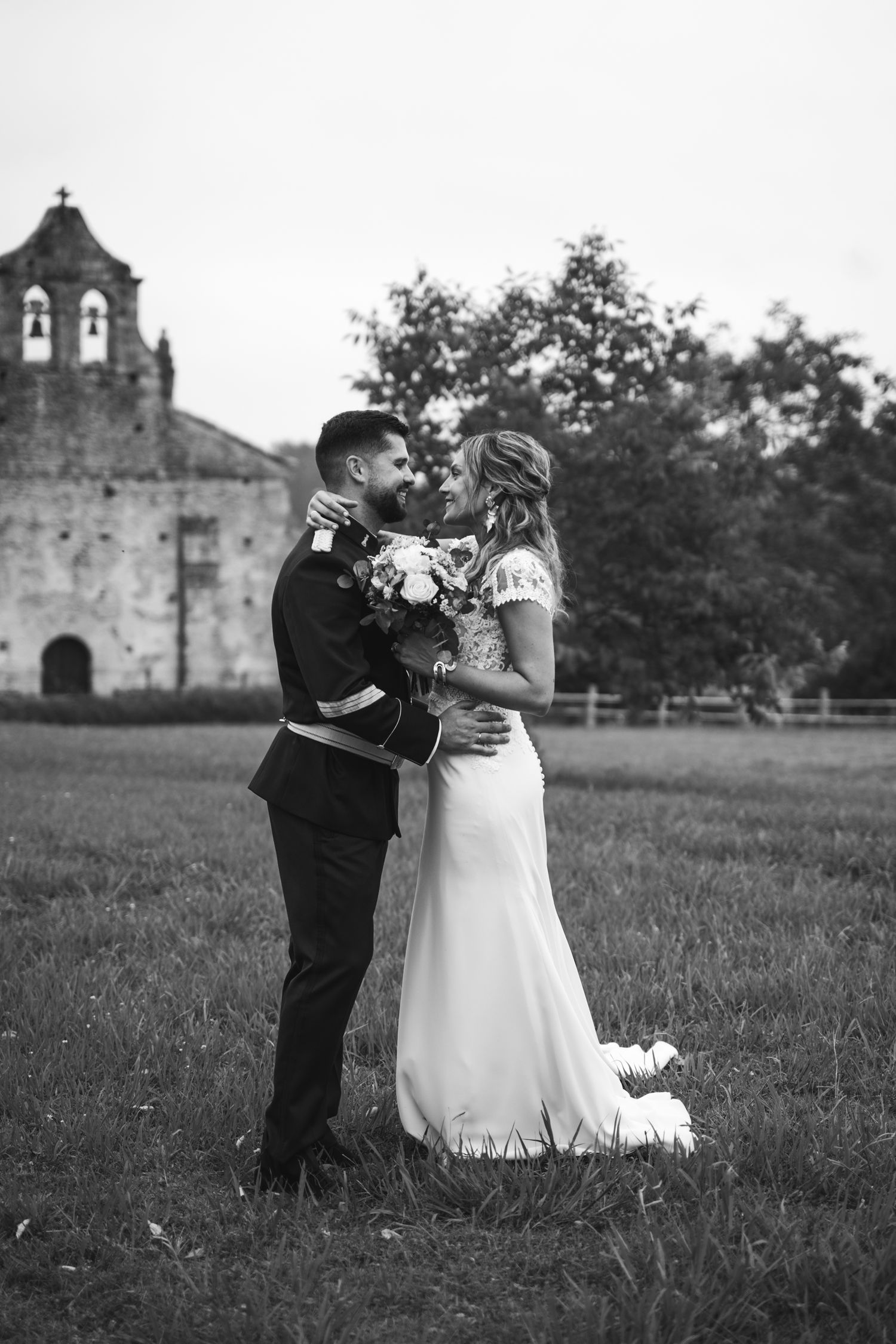A romantic black and white wedding portrait with a historic church in the background.