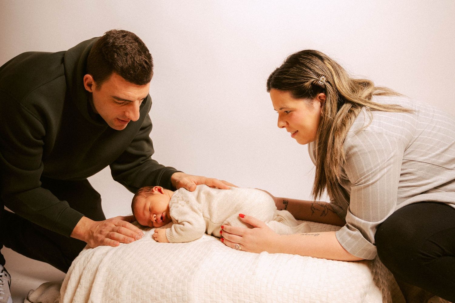 A series of six tender photographs showing parents bonding with their newborn baby on a white backdrop.