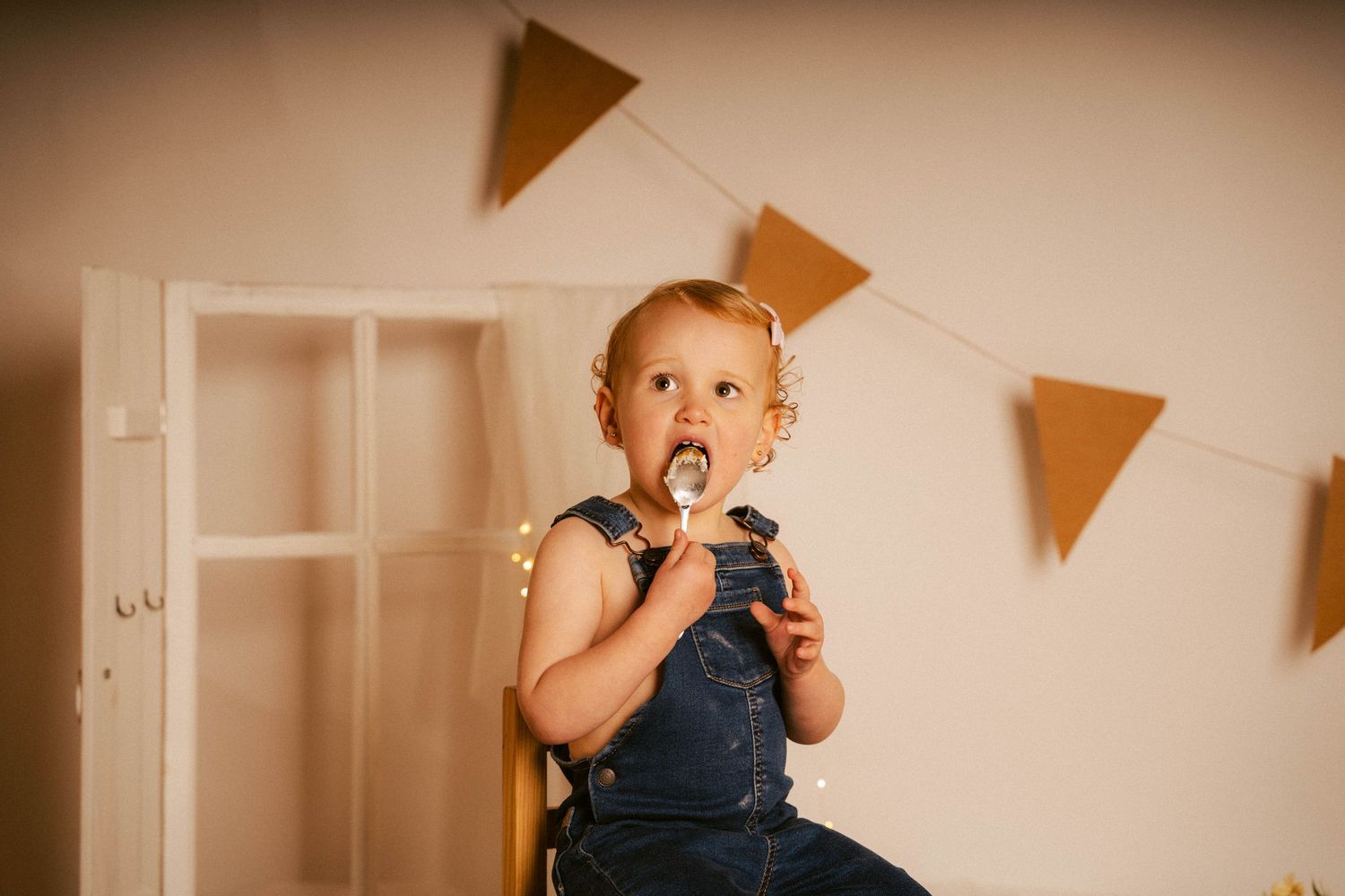 A series of warm-toned photos showing a child eating cake at a birthday party with orange triangle banners in the background.