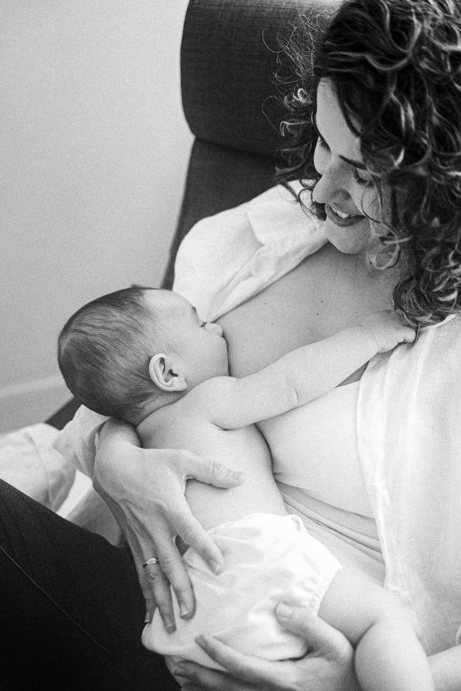 Intimate black and white nursing moment between parent and newborn.