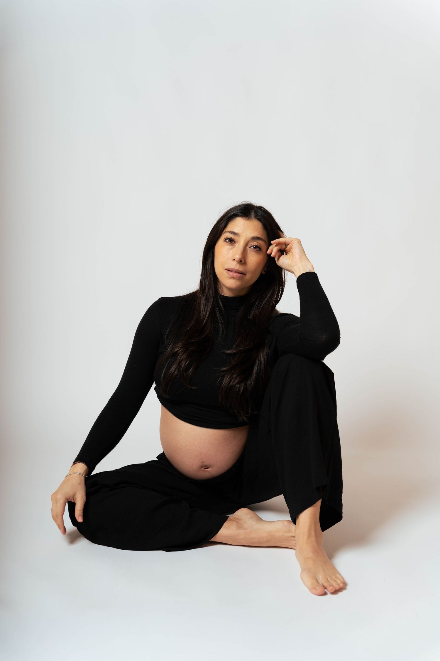 A figure in a black outfit poses artistically against a white background in a series of dramatic reclining positions.