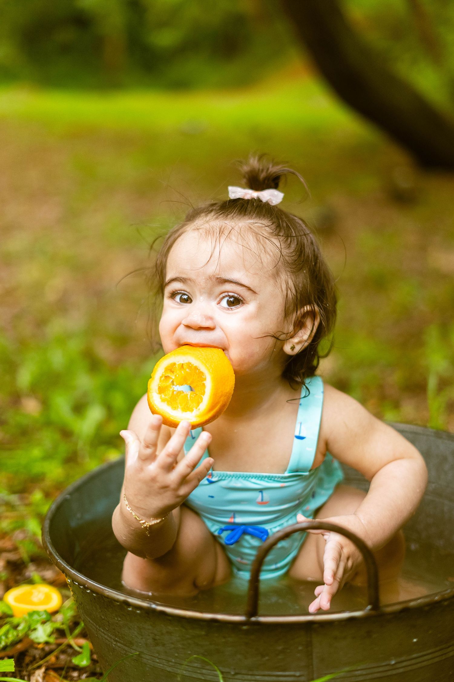 A small figure enjoys eating a fresh orange slice while sitting in a round container outdoors.