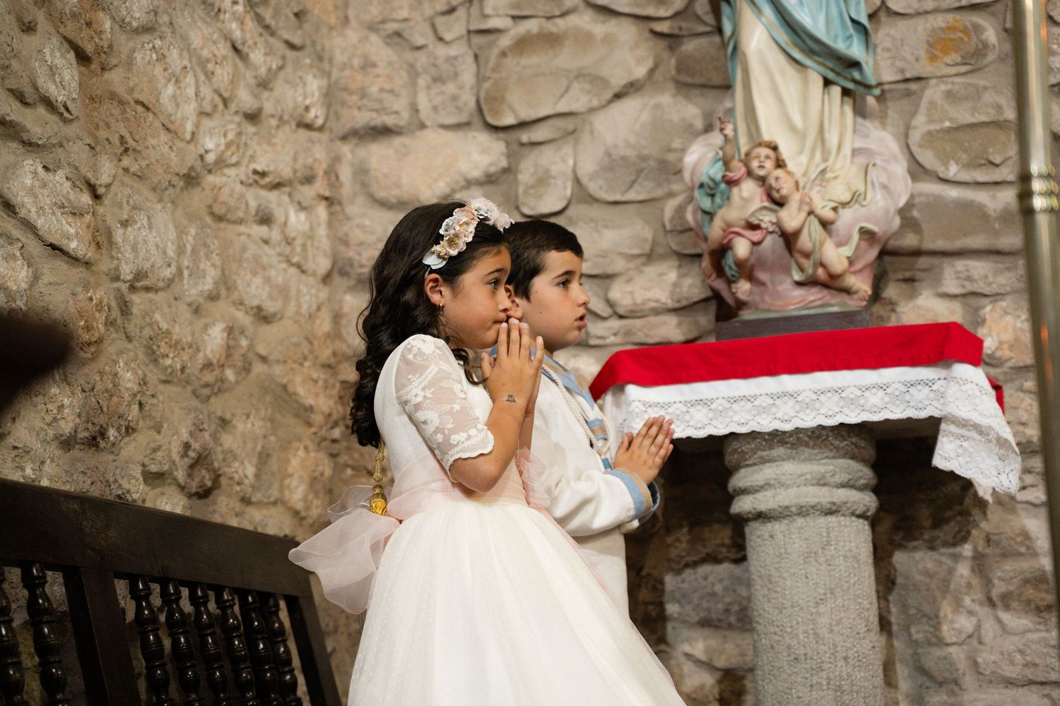 Children in formal attire pose inside stone church interior with traditional decorative elements.