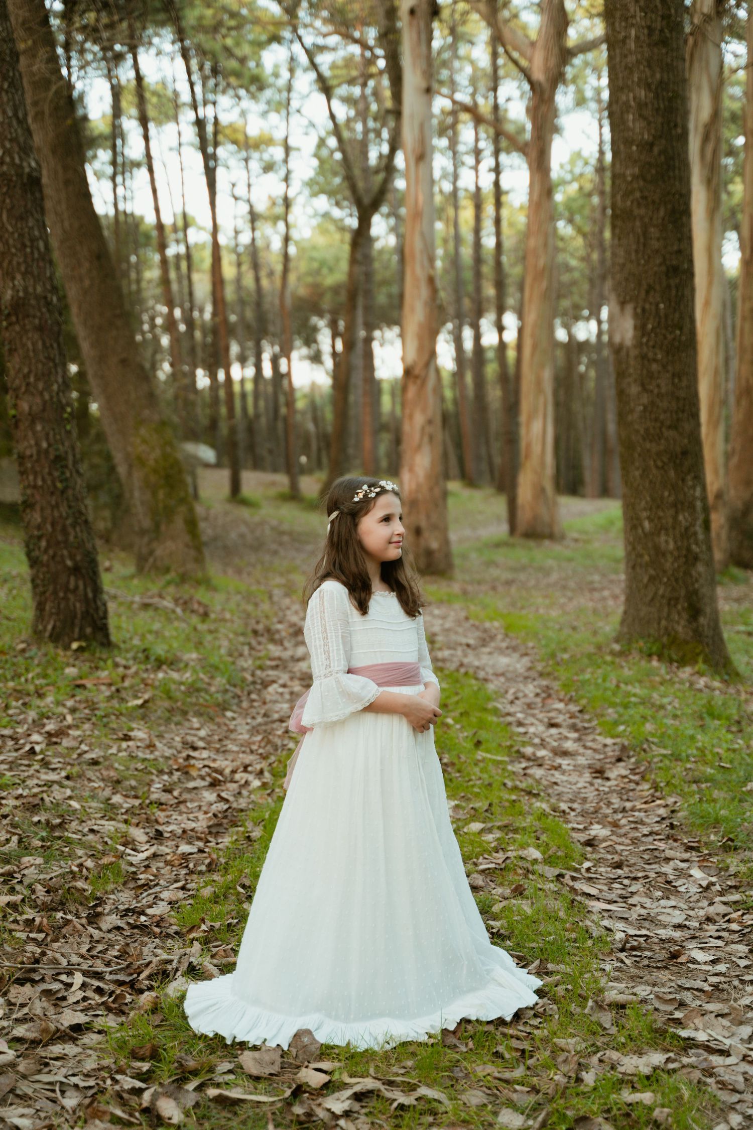 Enchanting forest path portrait featuring a flowing white dress with lace details.