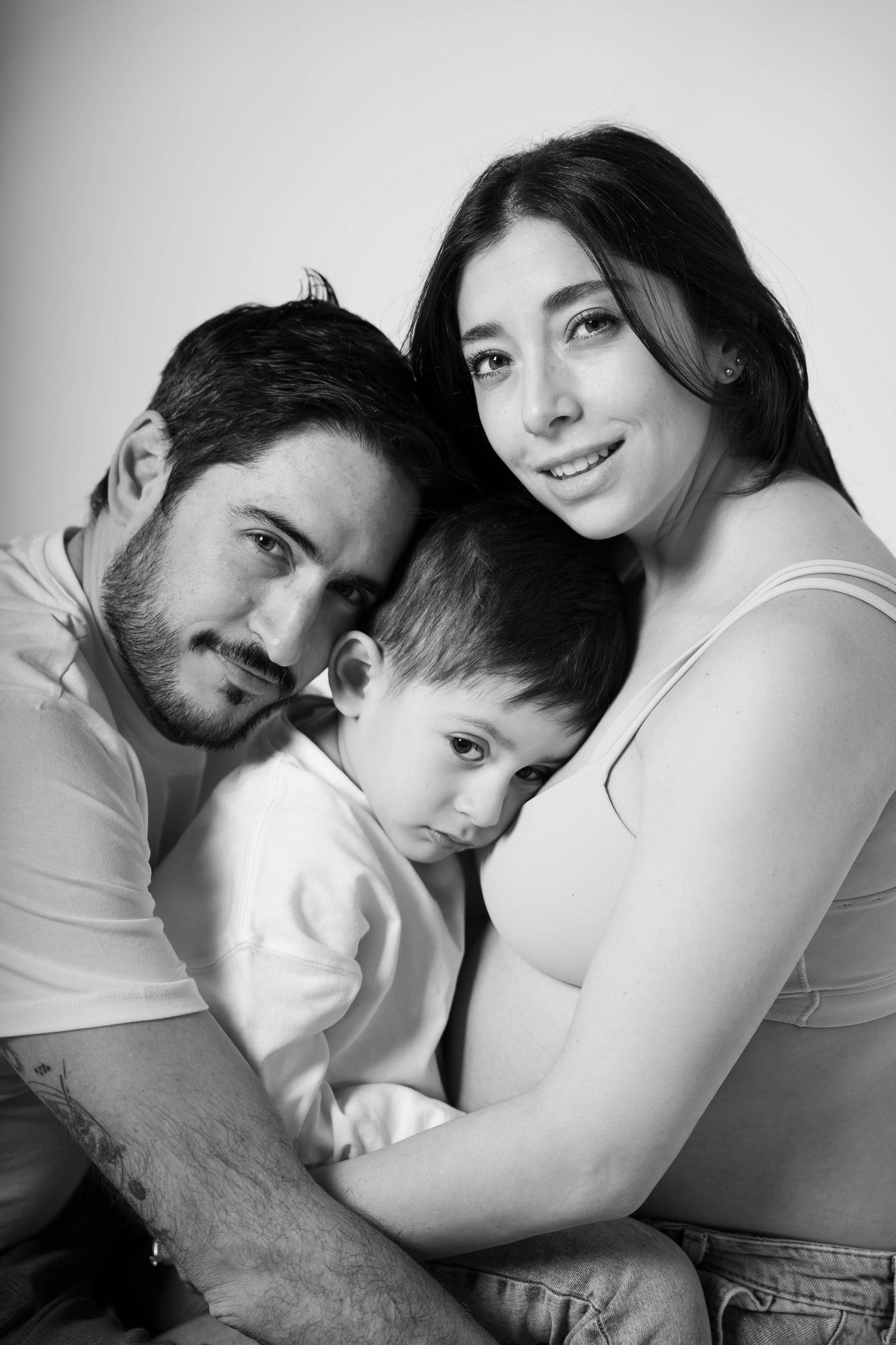 A series of intimate black and white pregnancy photos showing a tender moment between expecting parents.