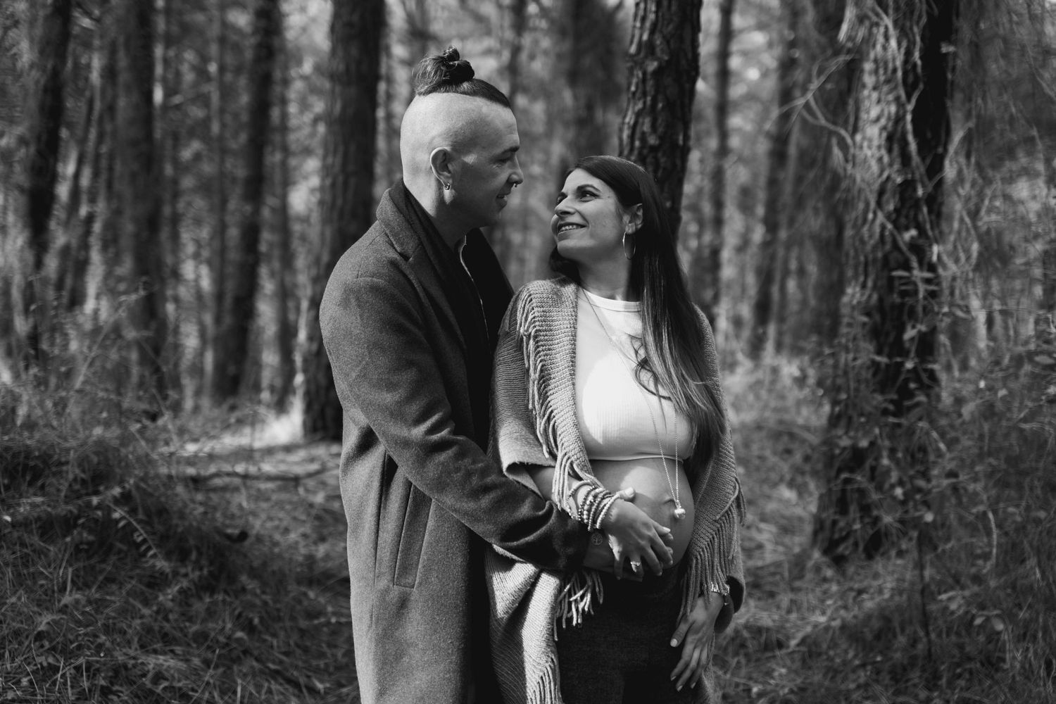 Black and white maternity photo showcasing an intimate moment in a forest setting.
