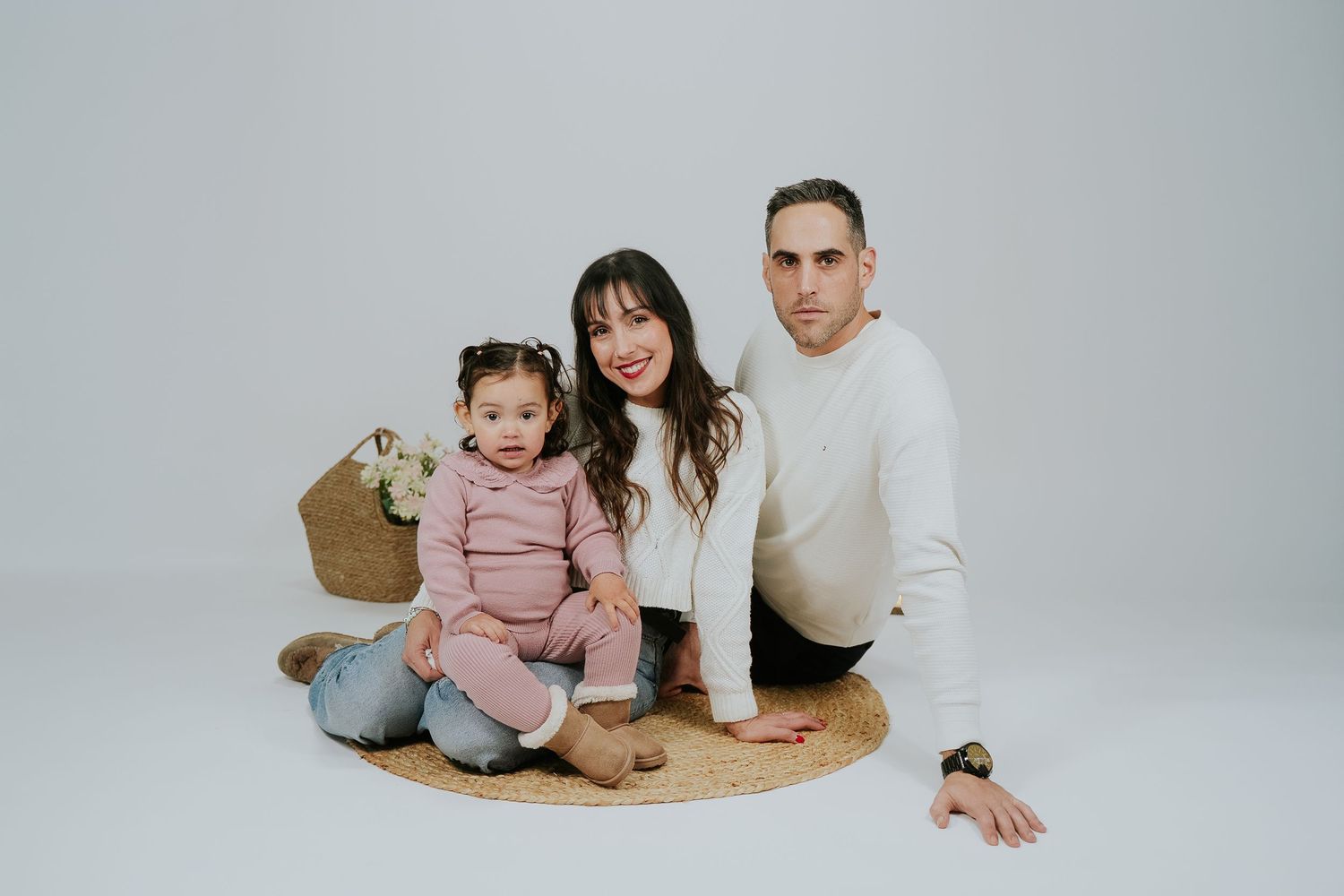 Family lounging together on white backdrop during studio photoshoot.
