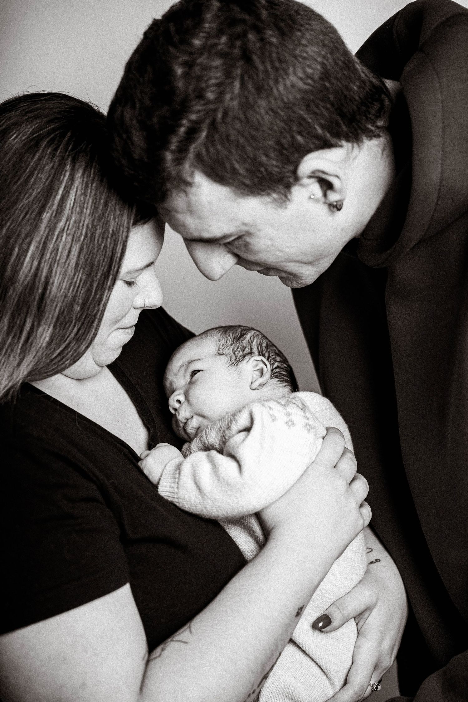 A series of intimate black and white photographs showing tender moments between parents and their newborn baby.