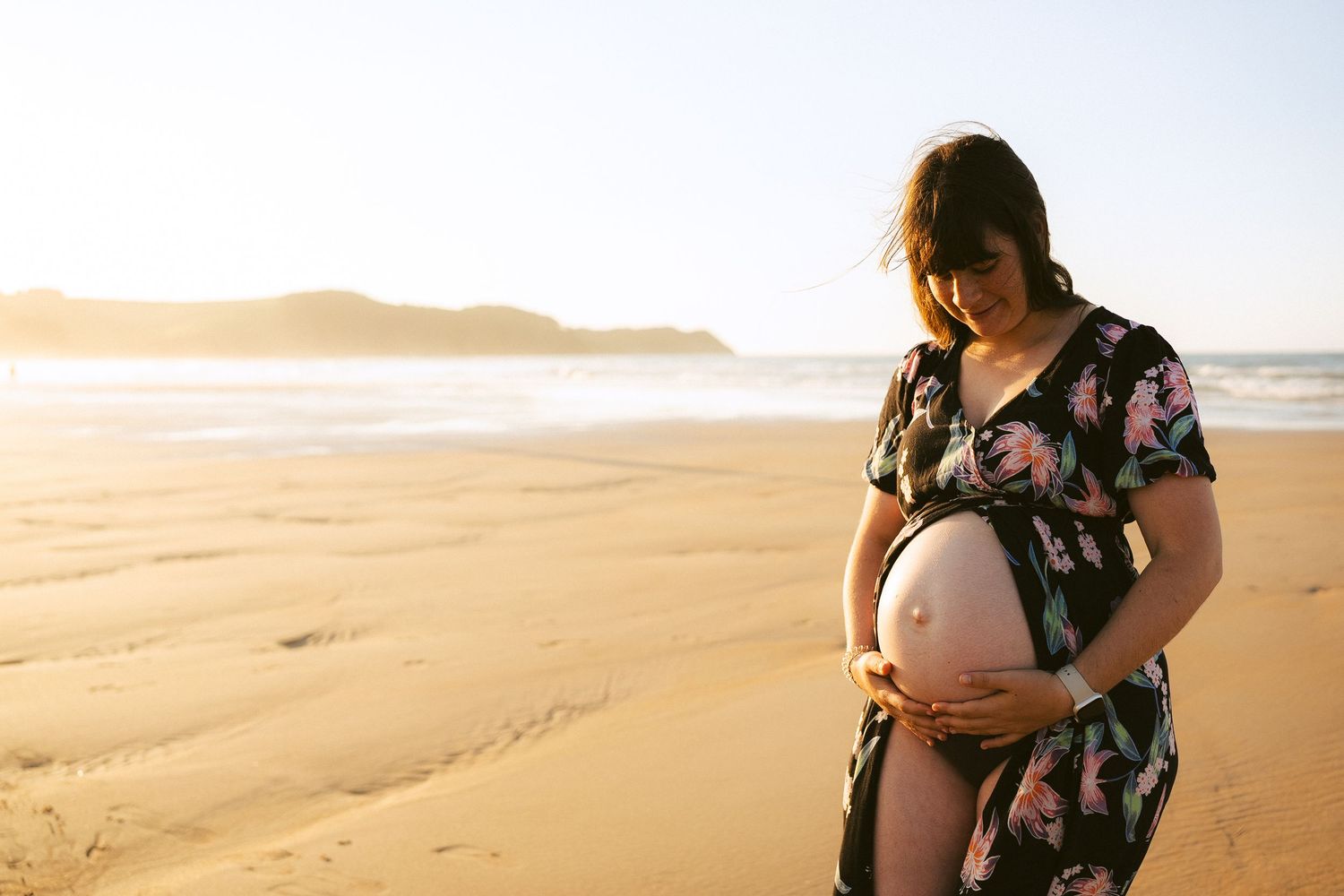 Maternity photo session on golden sandy beach at sunset.