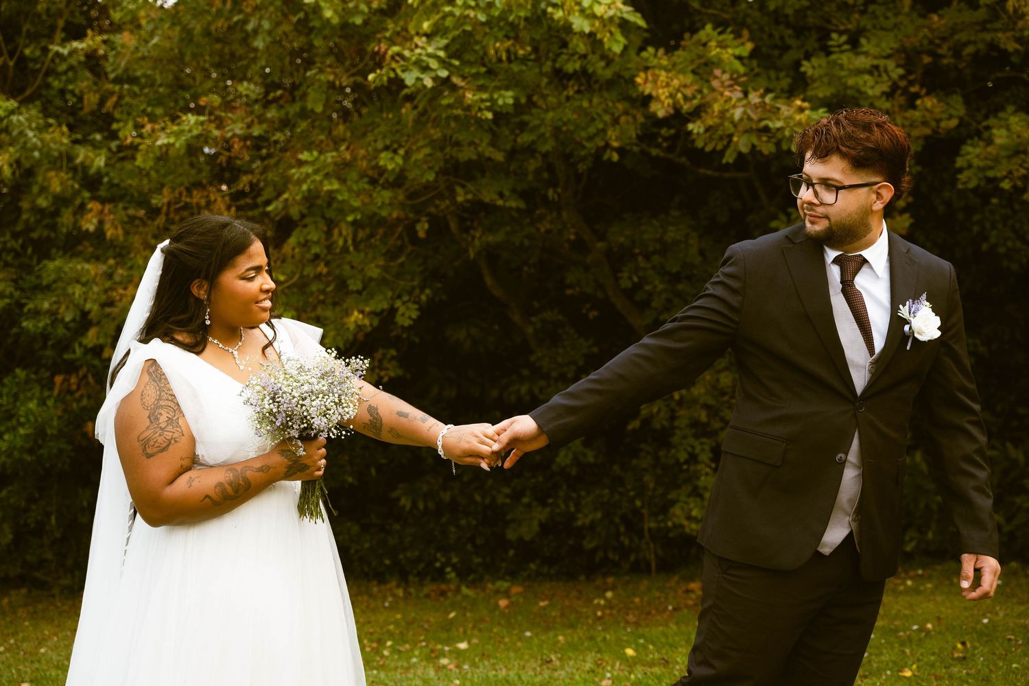 A couple shares a playful moment in a garden setting during their wedding photoshoot.