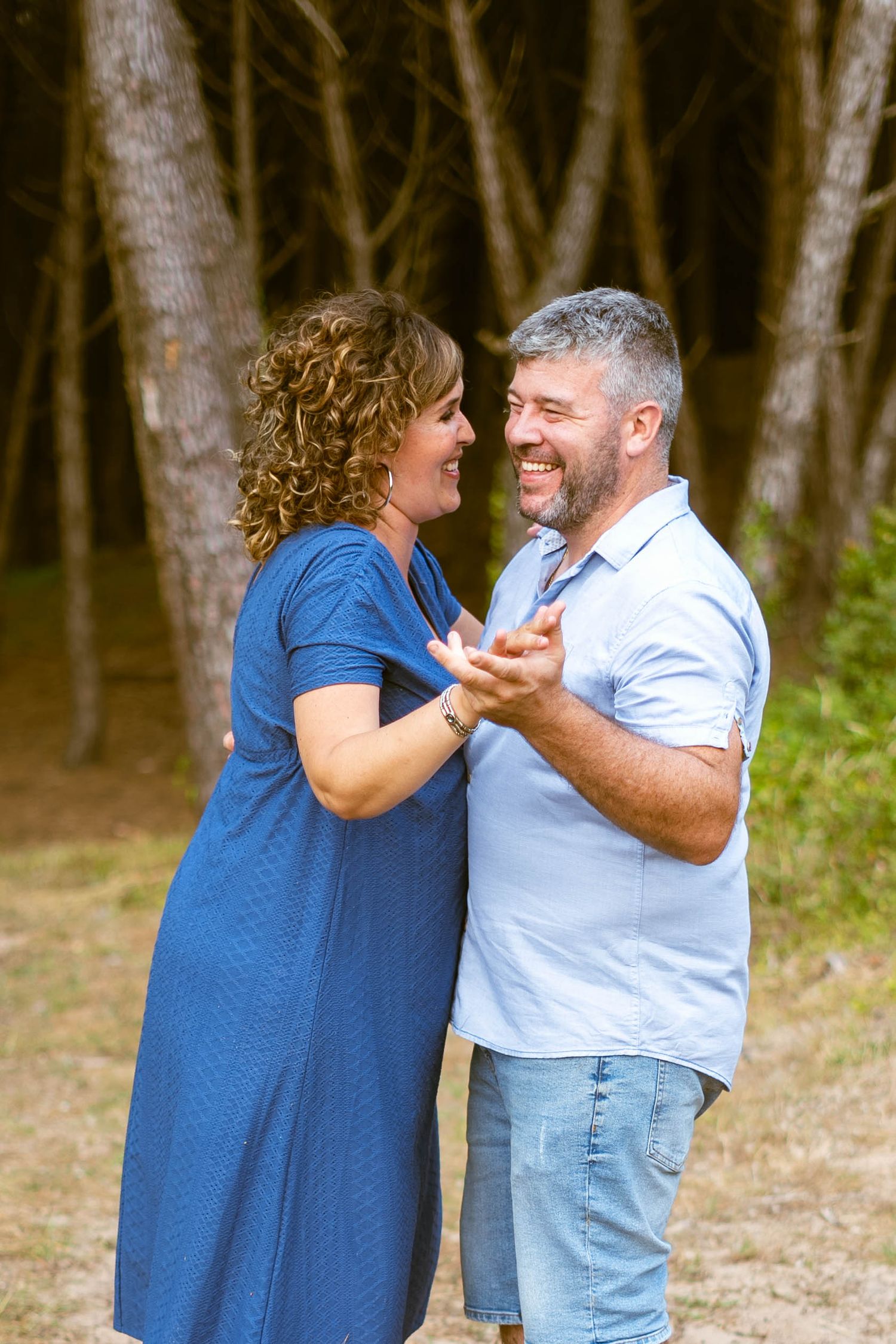 Couple in blue and white outfits sharing a joyful moment outdoors.