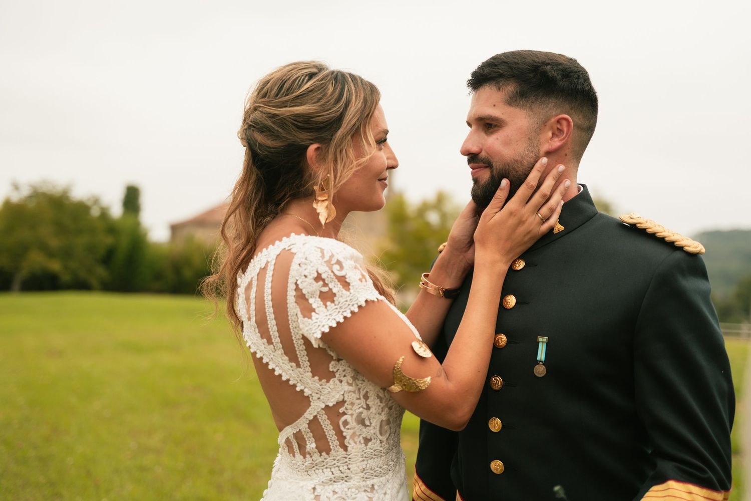 Couple embraces emotionally during wedding ceremony in outdoor field setting.