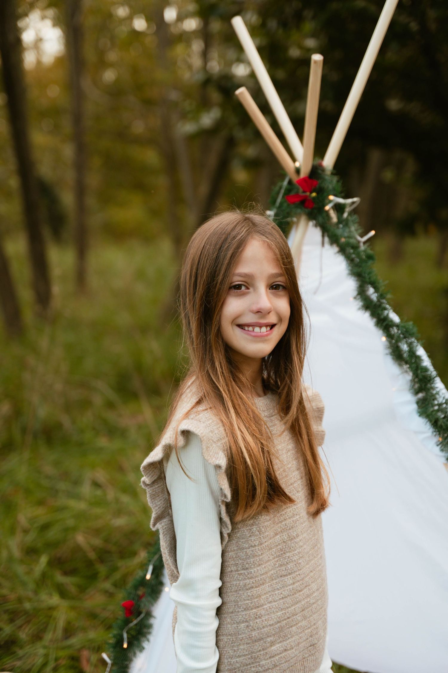 A sequence of portraits showing a young girl in a beige sweater posing against a festive holiday backdrop outdoors.