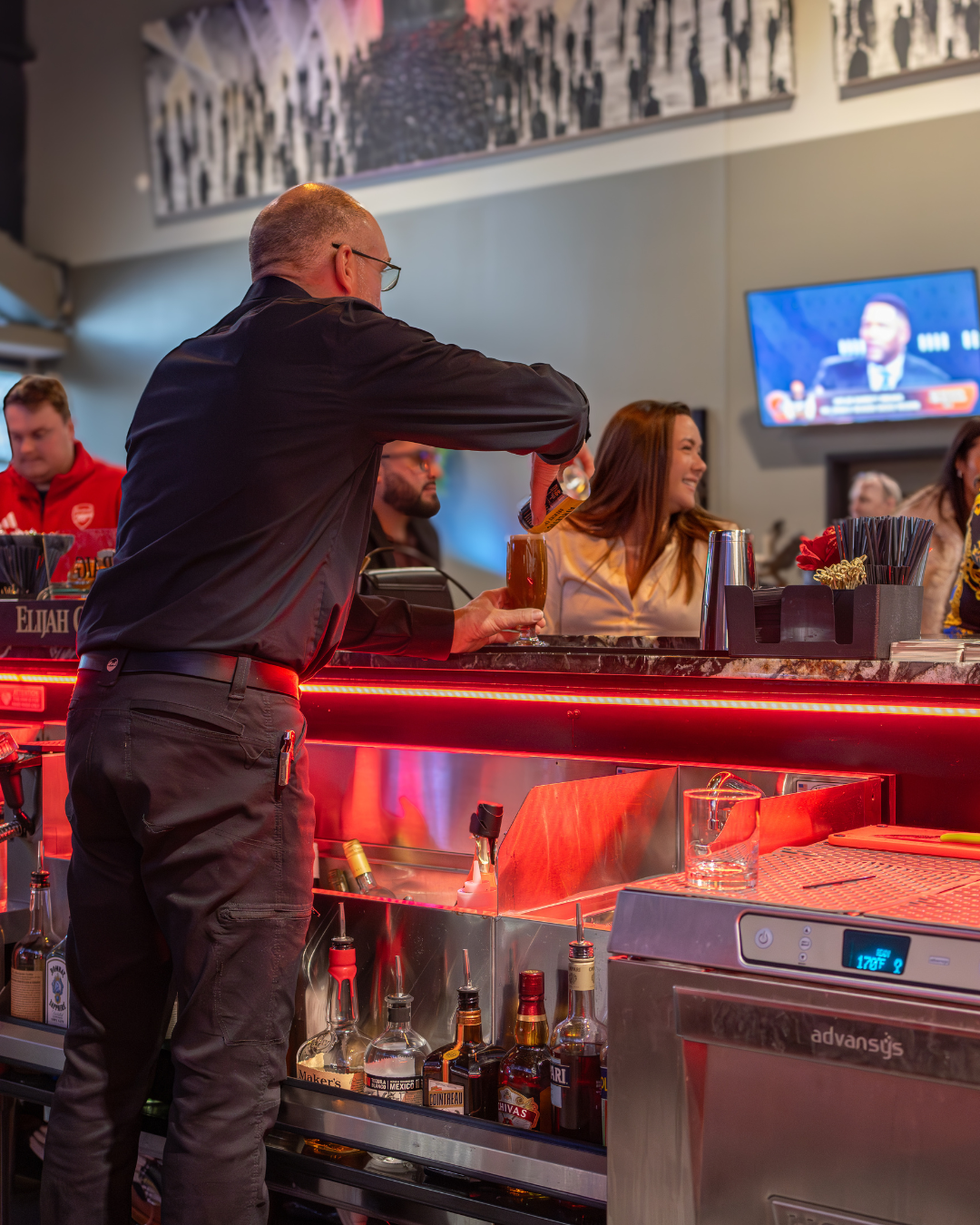 Bartender working behind a warmly lit bar, captured for hospitality, restaurant, and brand storytelling by Katelyn Lucas Photography.