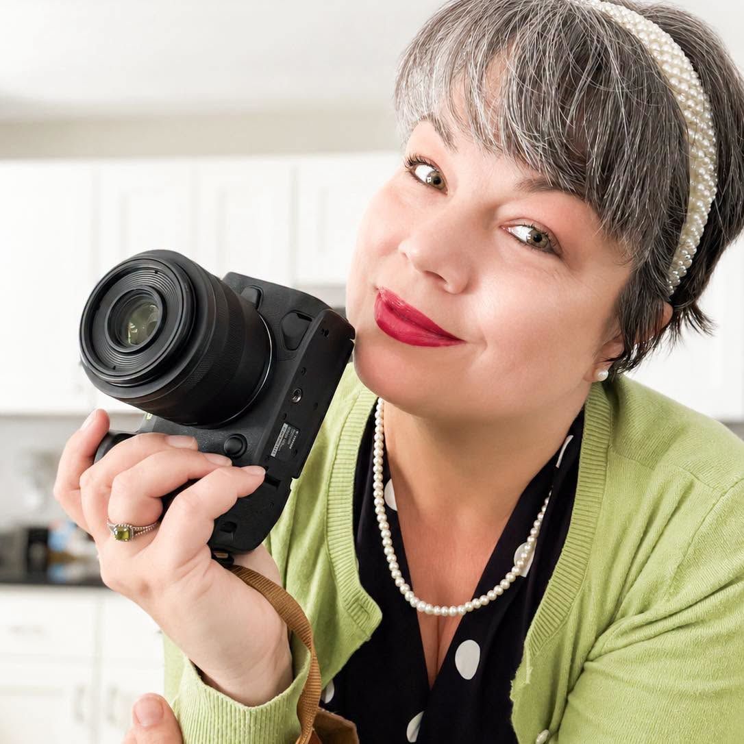 Katelyn Lucas holding a camera for a photographer portrait, representing brand photography and visual storytelling.