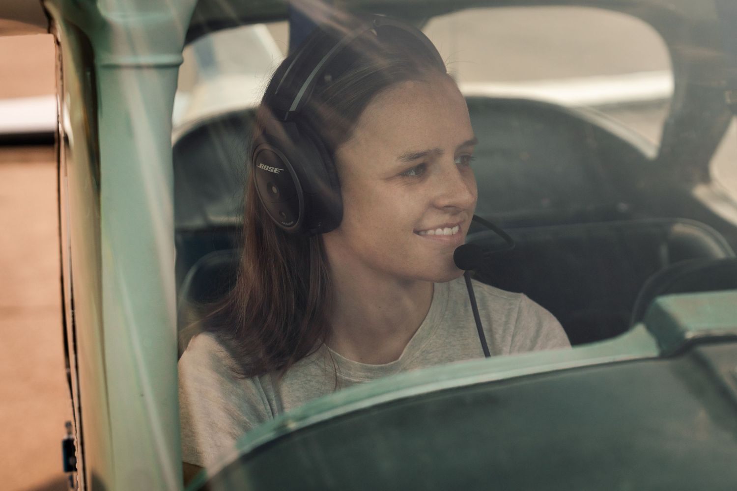 Female pilot wearing headset inside cockpit during candid aviation portrait session at Booneville Airport Arkansas