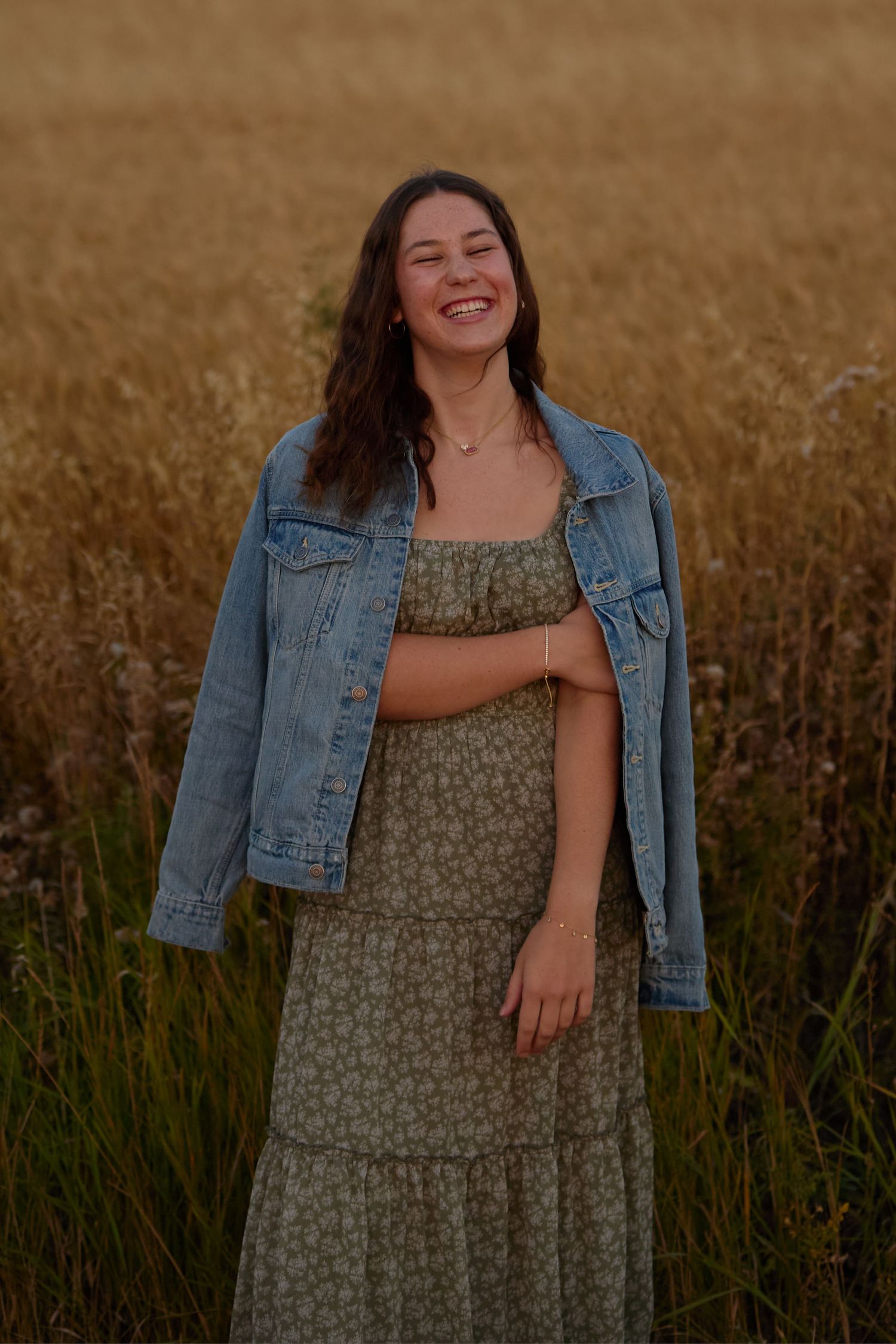 Candid outdoor portraits in a field wearing denim jacket and floral dress.