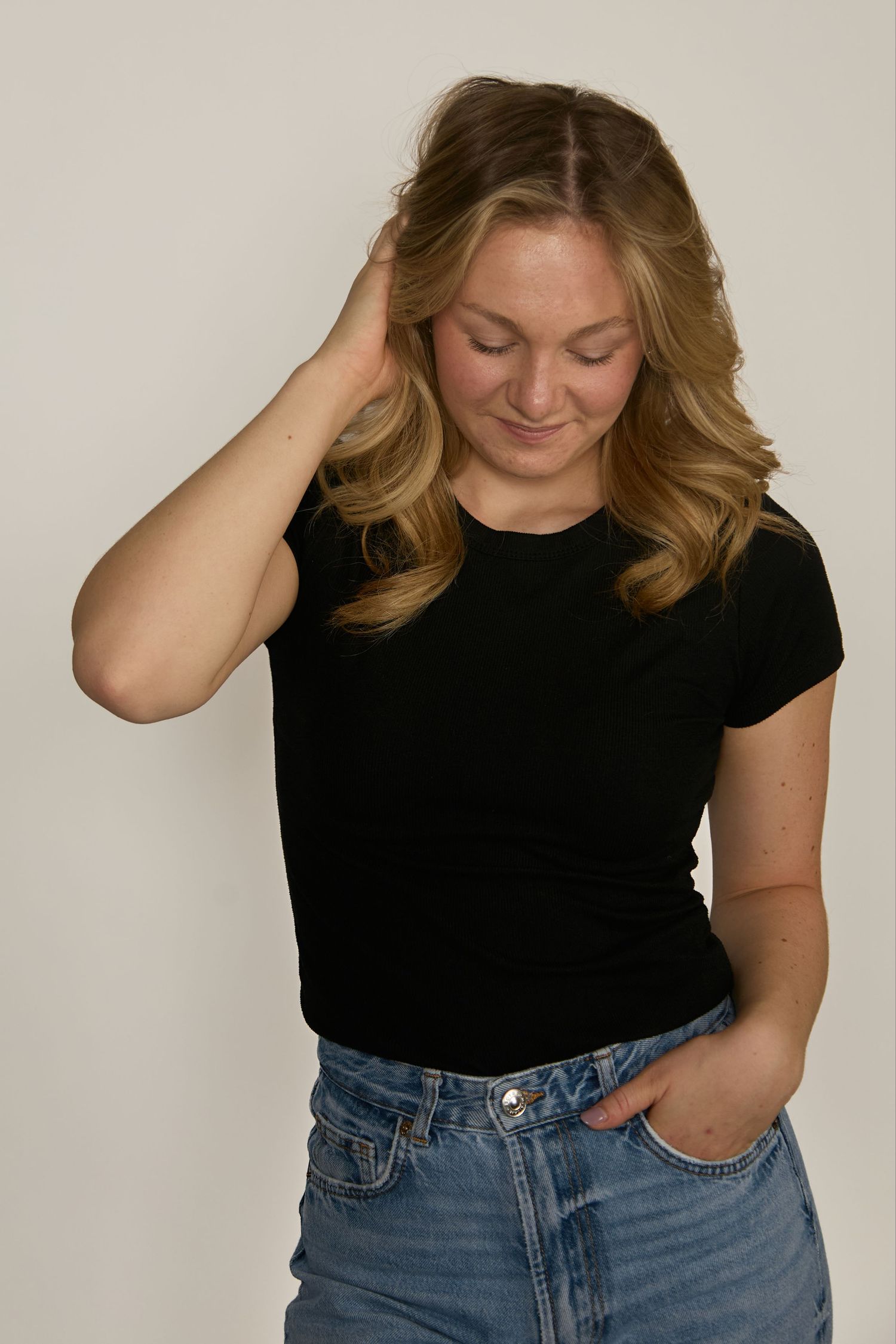 A person in a black t-shirt and blue jeans poses against a light background in a series of casual shots.
