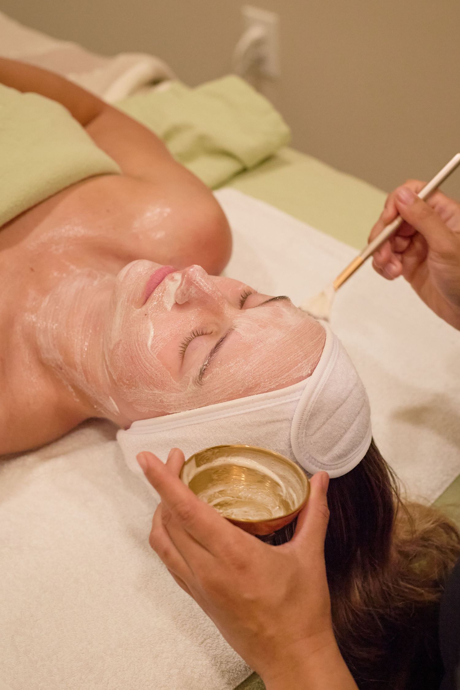 A person receiving a luxurious facial treatment with a golden mask being applied at a spa.