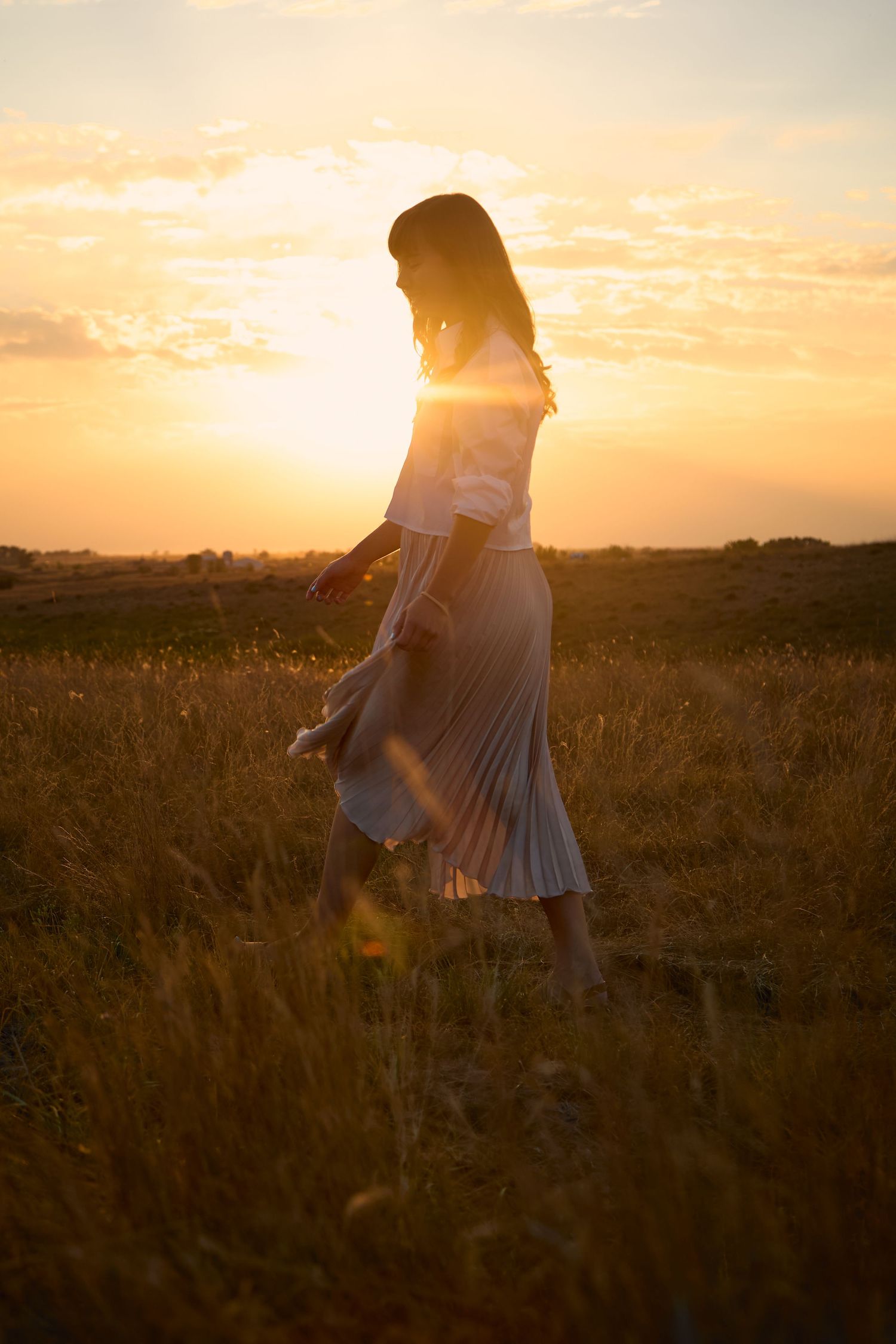 Dreamy golden hour photography in a field with flowing dress movement.
