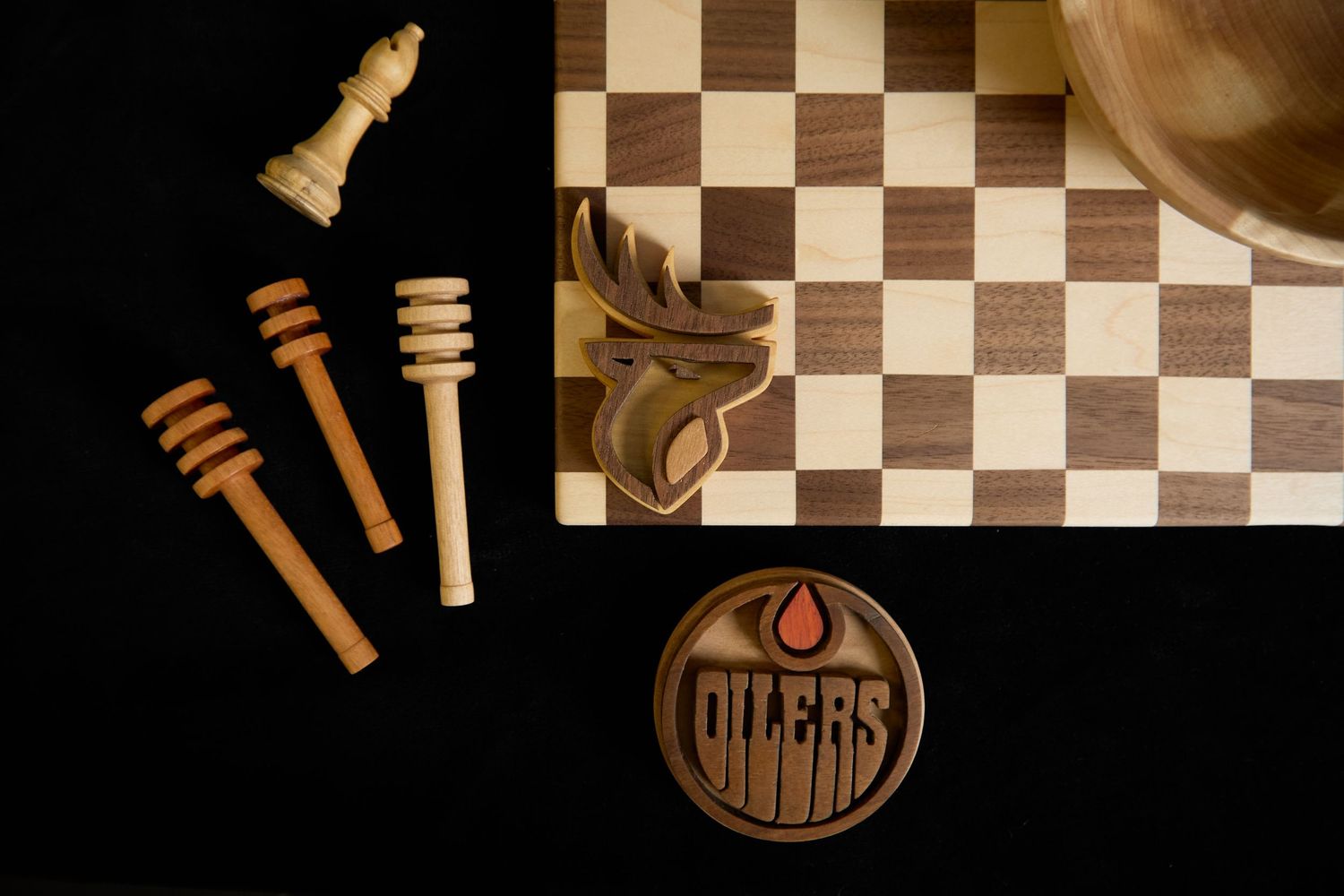 Overhead view of chess pieces, wooden board, and Edmonton Oilers logo on black background.