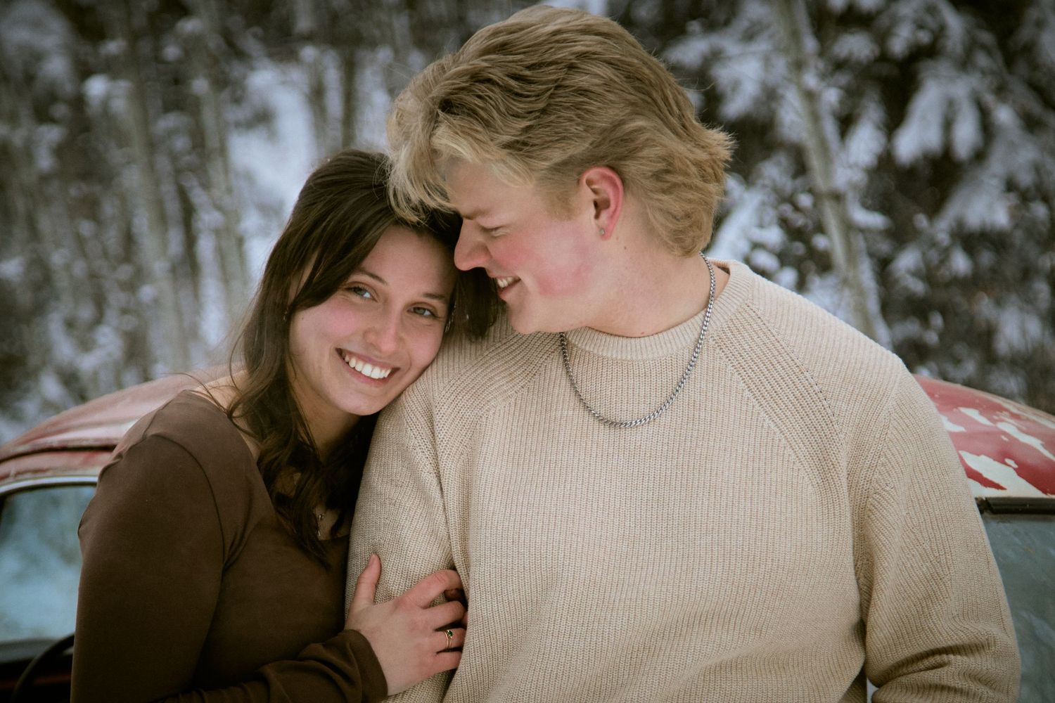 A couple sharing intimate moments together while sitting outdoors in winter weather.