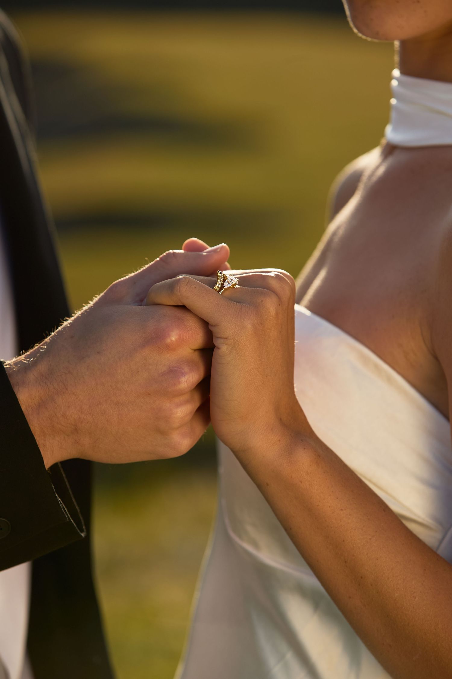 Close-up of hands holding a pen and writing on white paper outdoors during golden hour lighting.