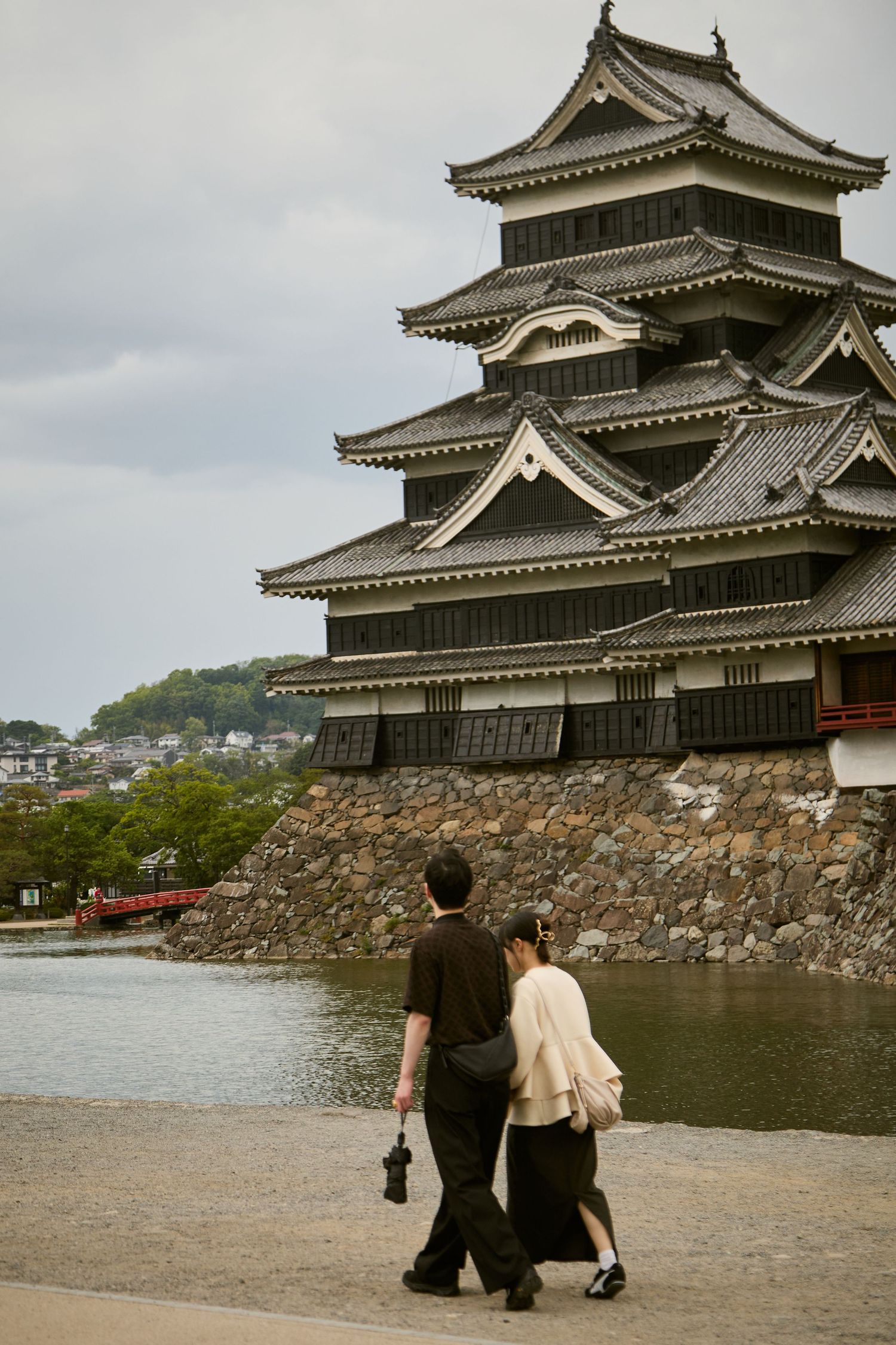 Couple walking along the moat of Matsumoto Castle, a historic black Japanese feudal castle in Nagano, Japan.