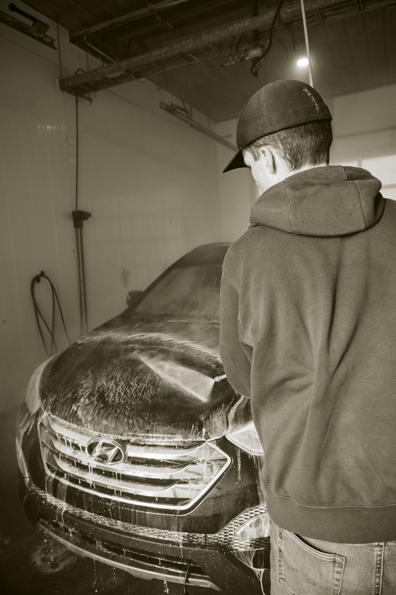 Black and white photo sequence showing a person wearing a hoodie with a car reflection visible across their back.