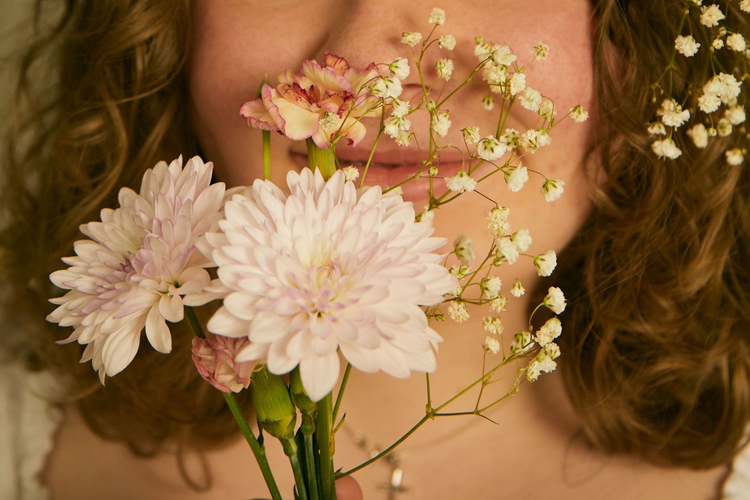 Delicate pink chrysanthemums and baby's breath flowers create a soft, romantic arrangement against a natural background.