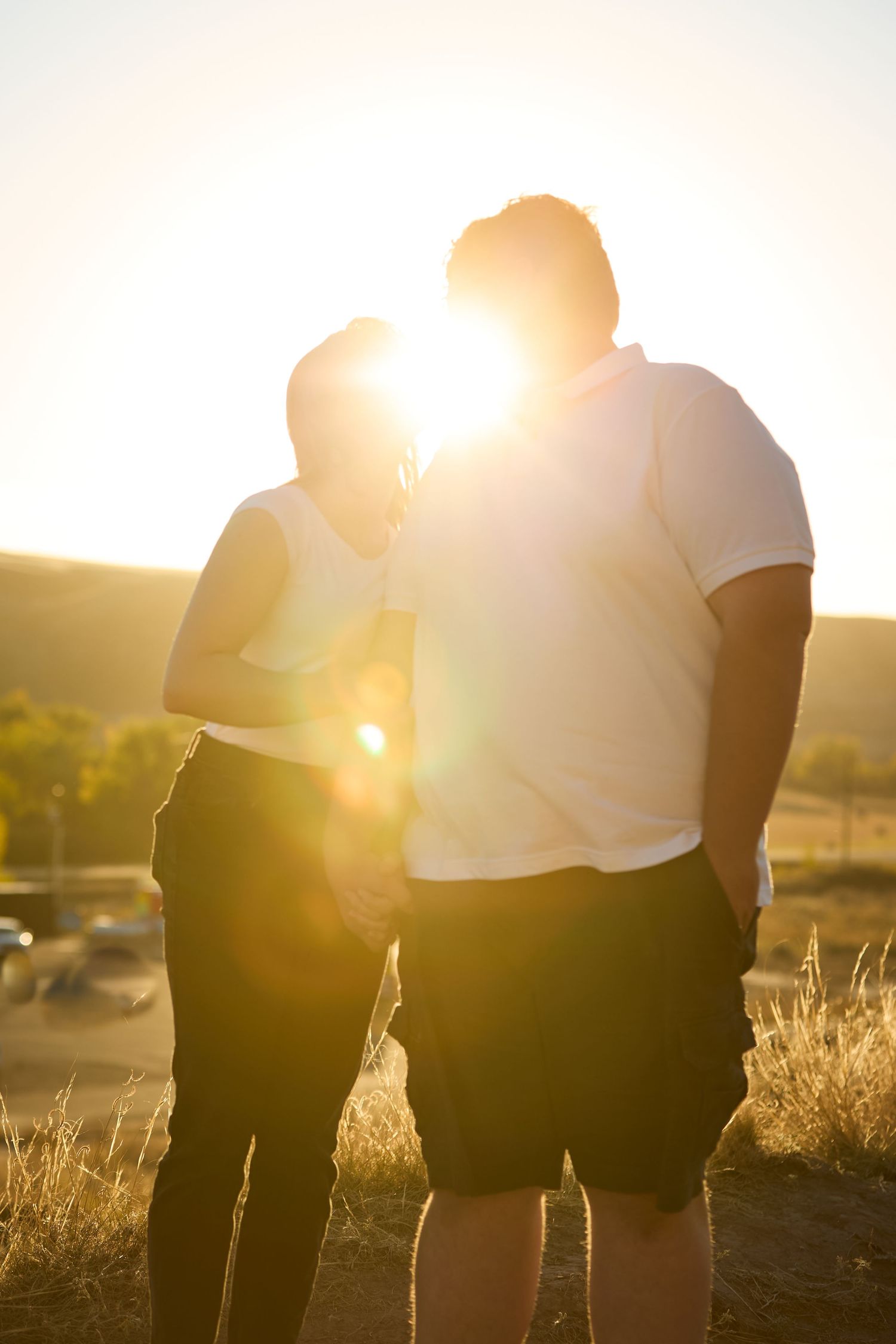 Silhouettes of a group standing together in a field at sunset with golden sunlight streaming through.