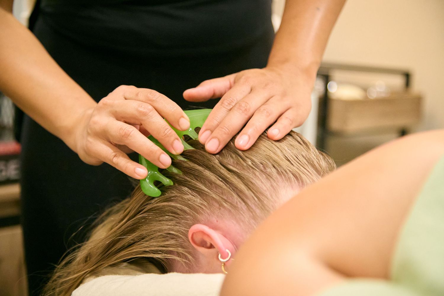 Therapist applying aloe vera to client's hair during a relaxing scalp treatment at a spa.