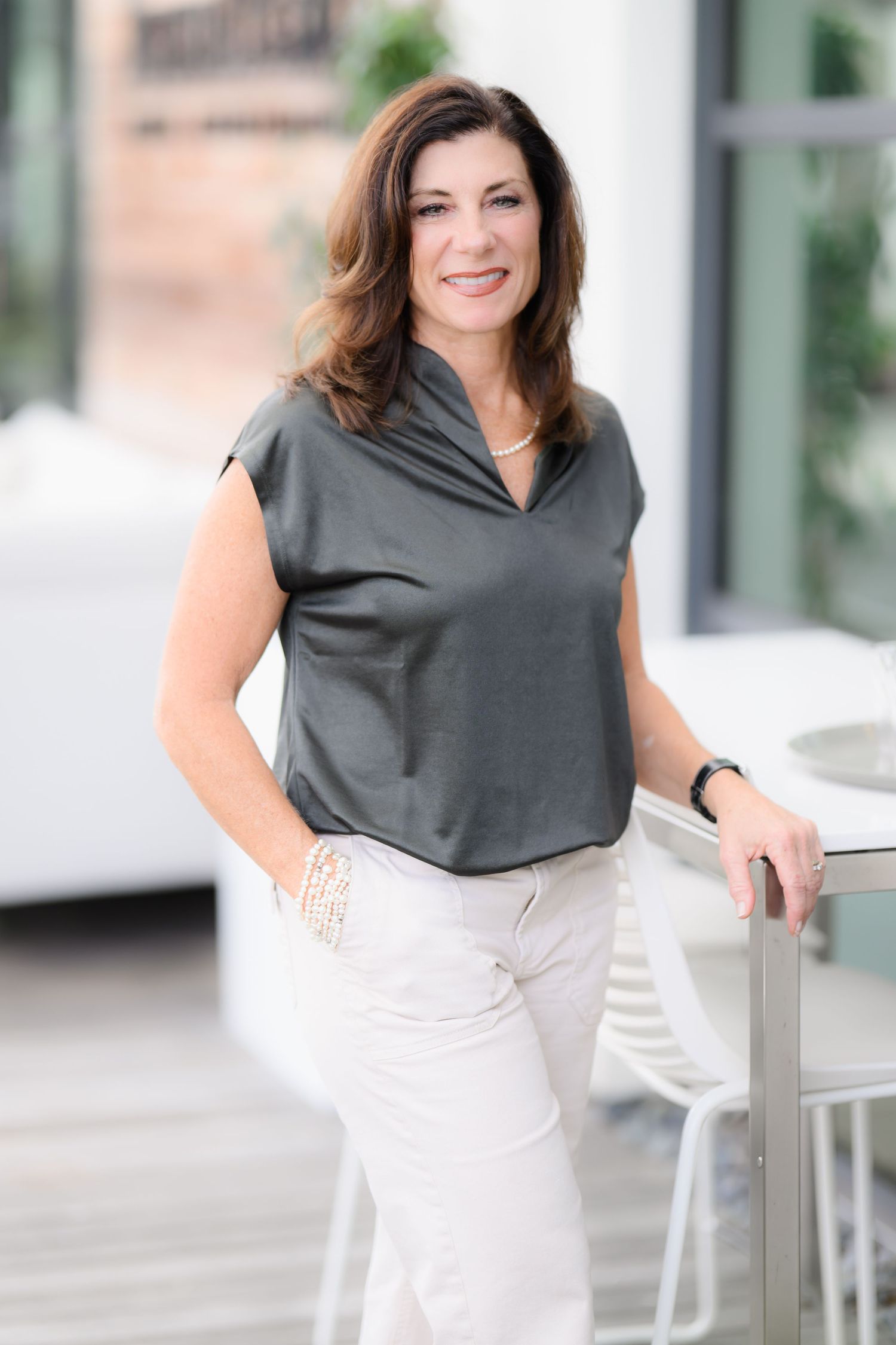Holly posing at the Westfield mall in San Diego wearing white pants and a gray top for her headshot and personal branding session