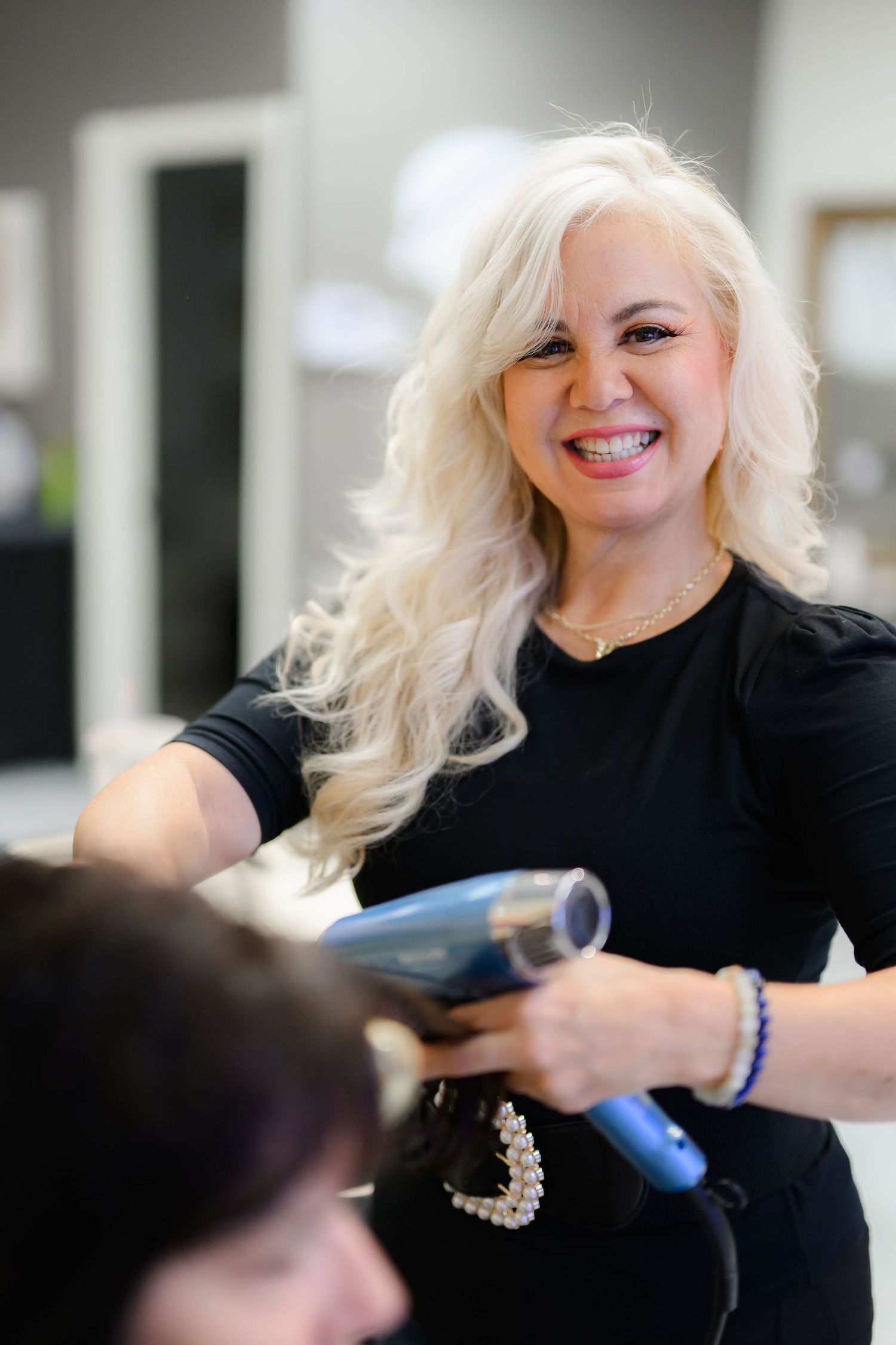 Lisa blow drying a clients hair in her salon in san Diego as part of her working oriented personal branding photoshoot.
