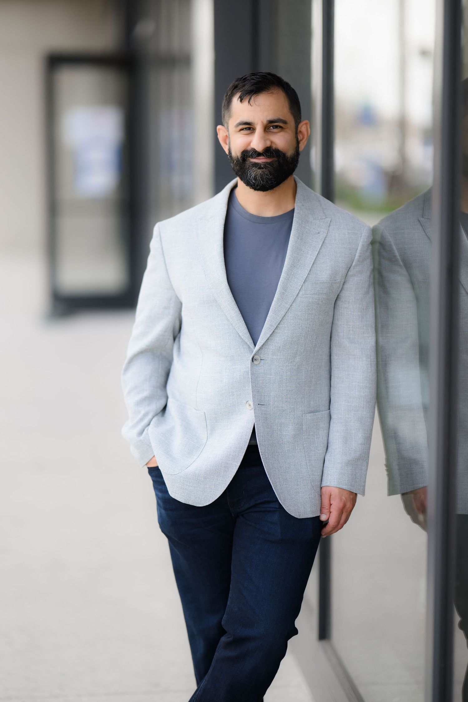 Ali wearing a gray jacket and darker gray shirt posing confidently for his new personal branding photoshoot in downtown San Diego