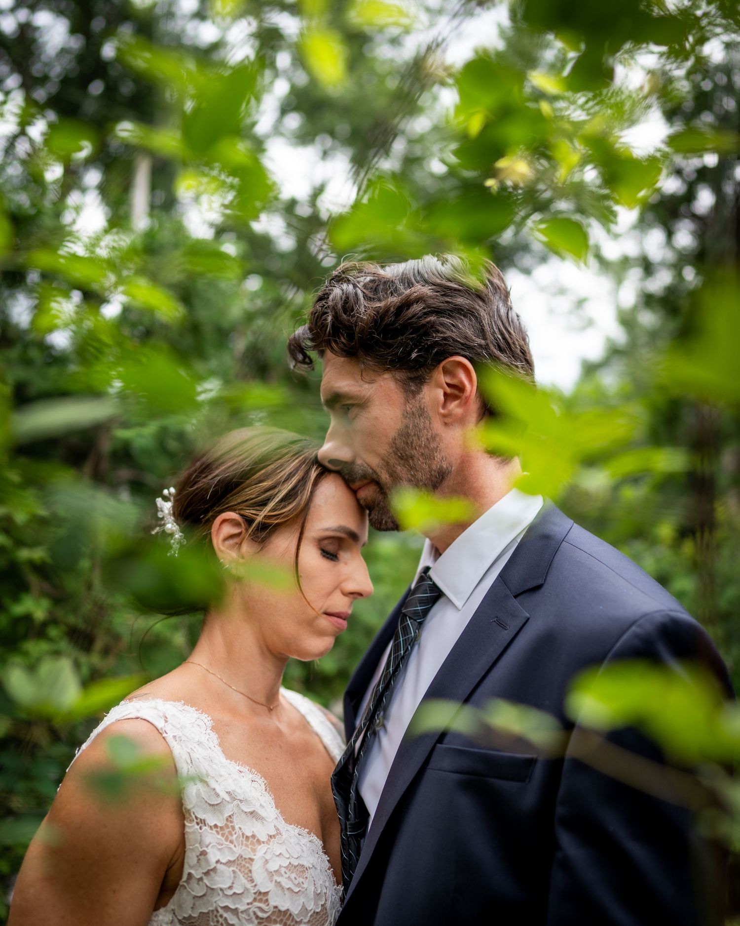 Bride and groom behind some foliage in Laval, Quebec