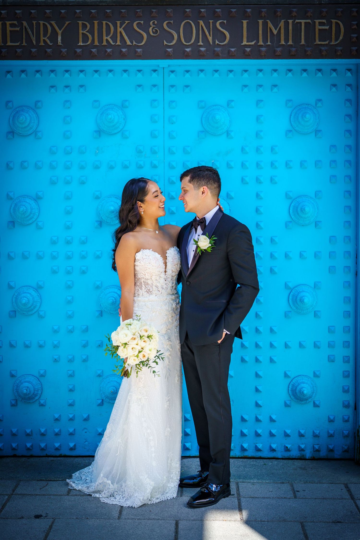 Newlyweds in front of the blue Birks door in downtown Montreal