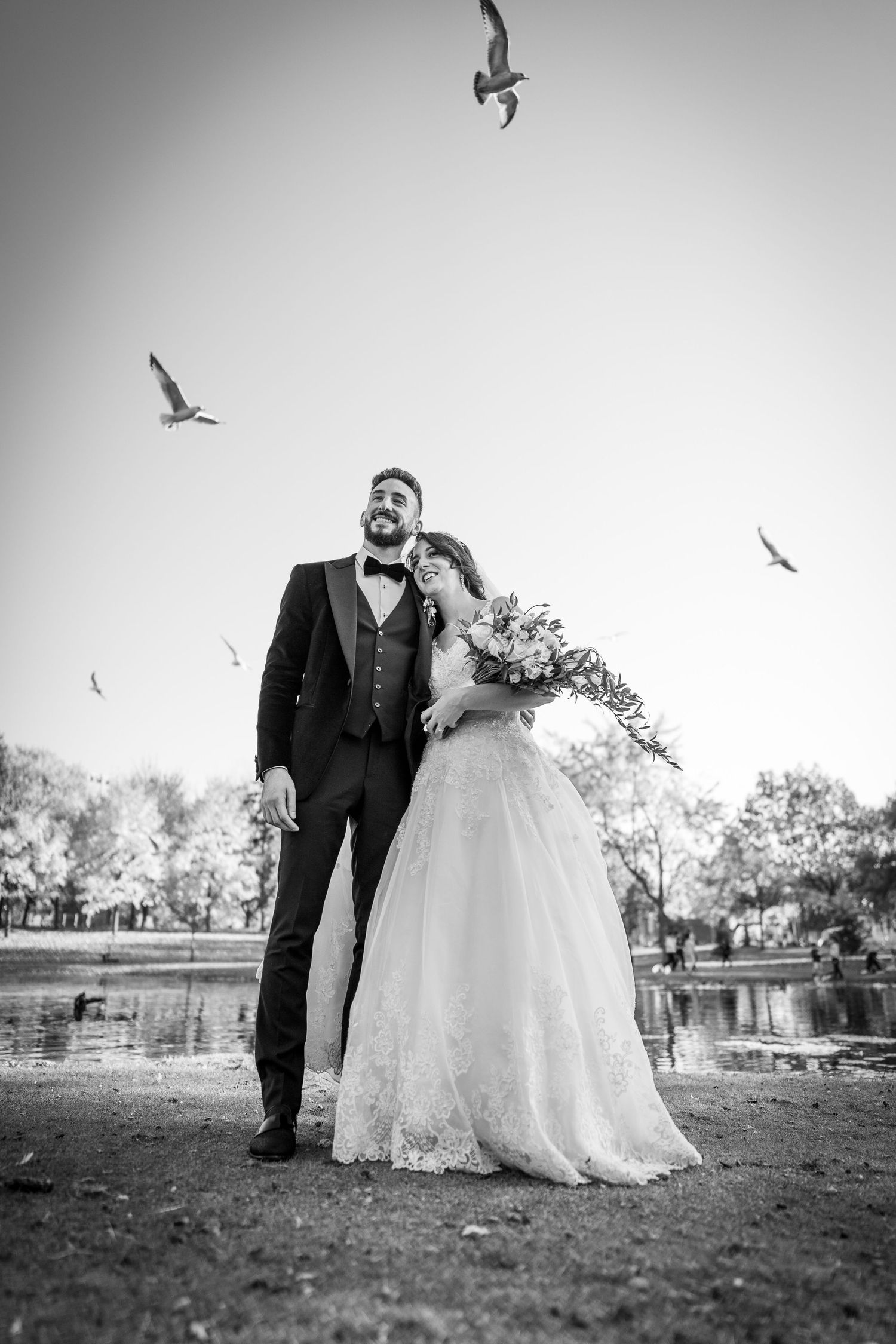 Bride and groom surrounded by flying birds in the park after their wedding