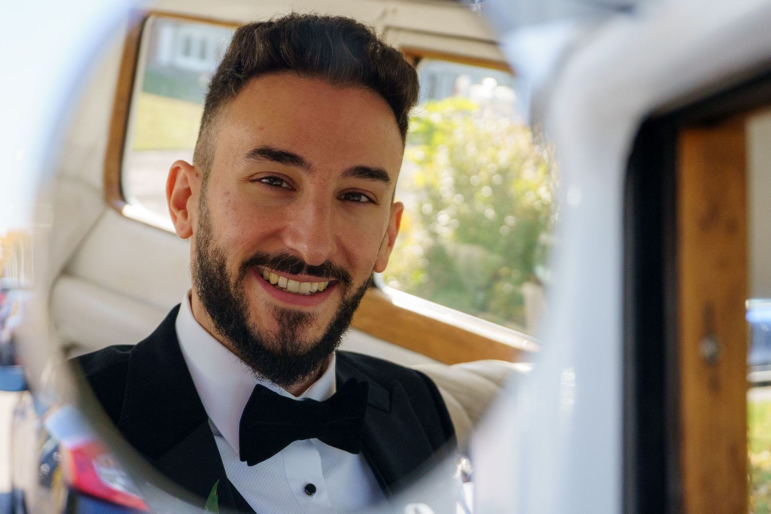 Close-up of groom through his wedding car mirror