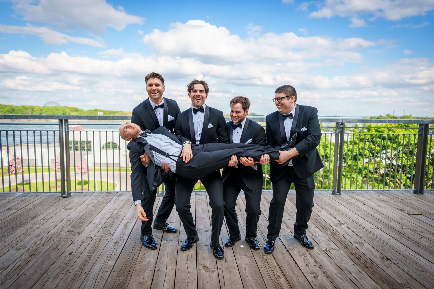 Groomsmen hold up groom at the Old Port in Montreal, Quebec