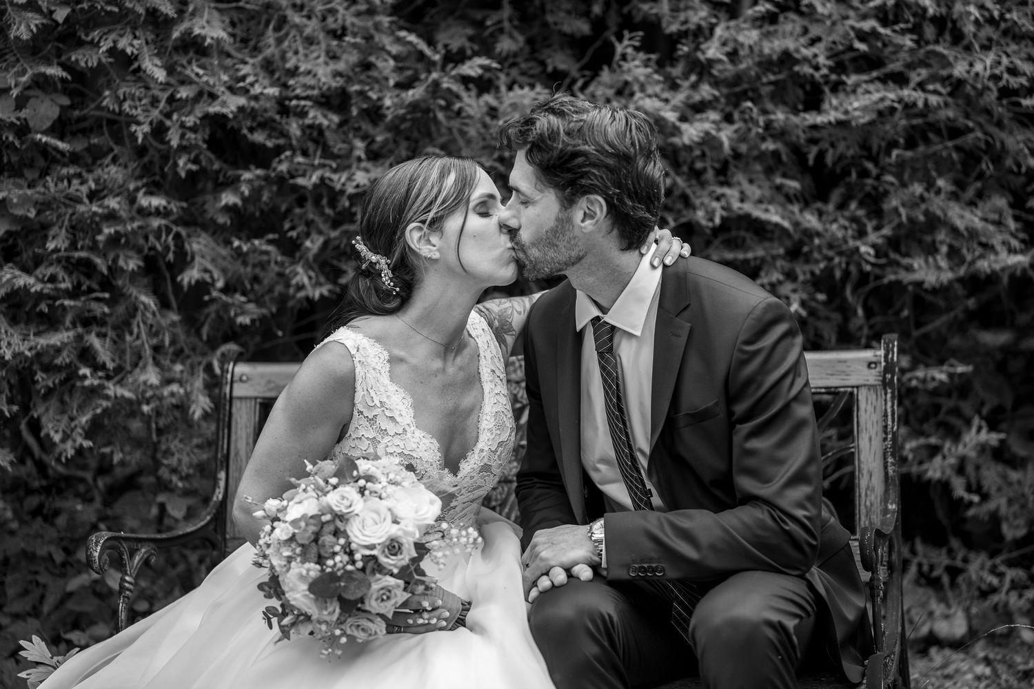 Bride and groom kissing on a bench in Laval, Quebec